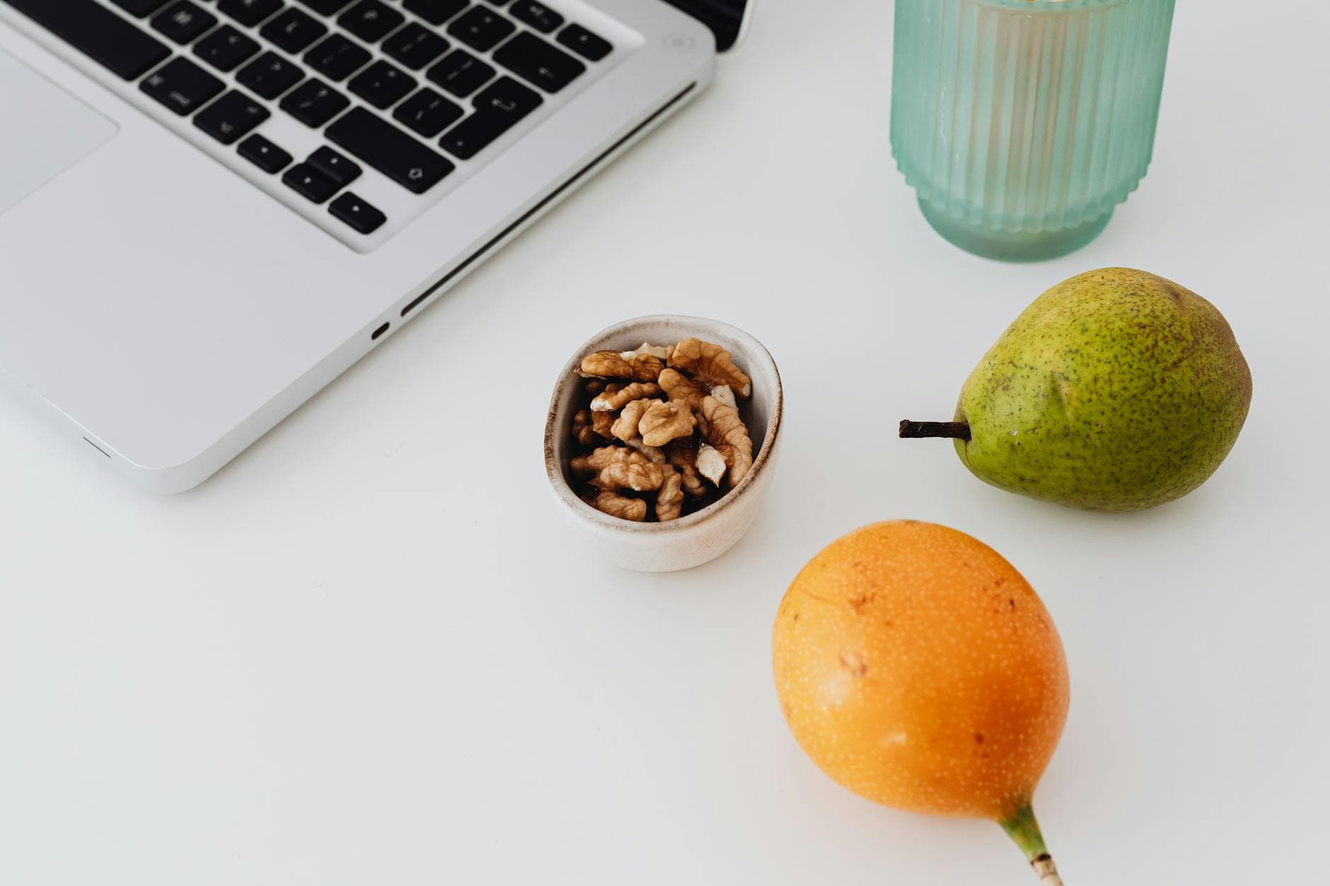 A desk setup featuring a laptop, fruits, and snacks for a productive and healthy work environment. - healthy work snacks