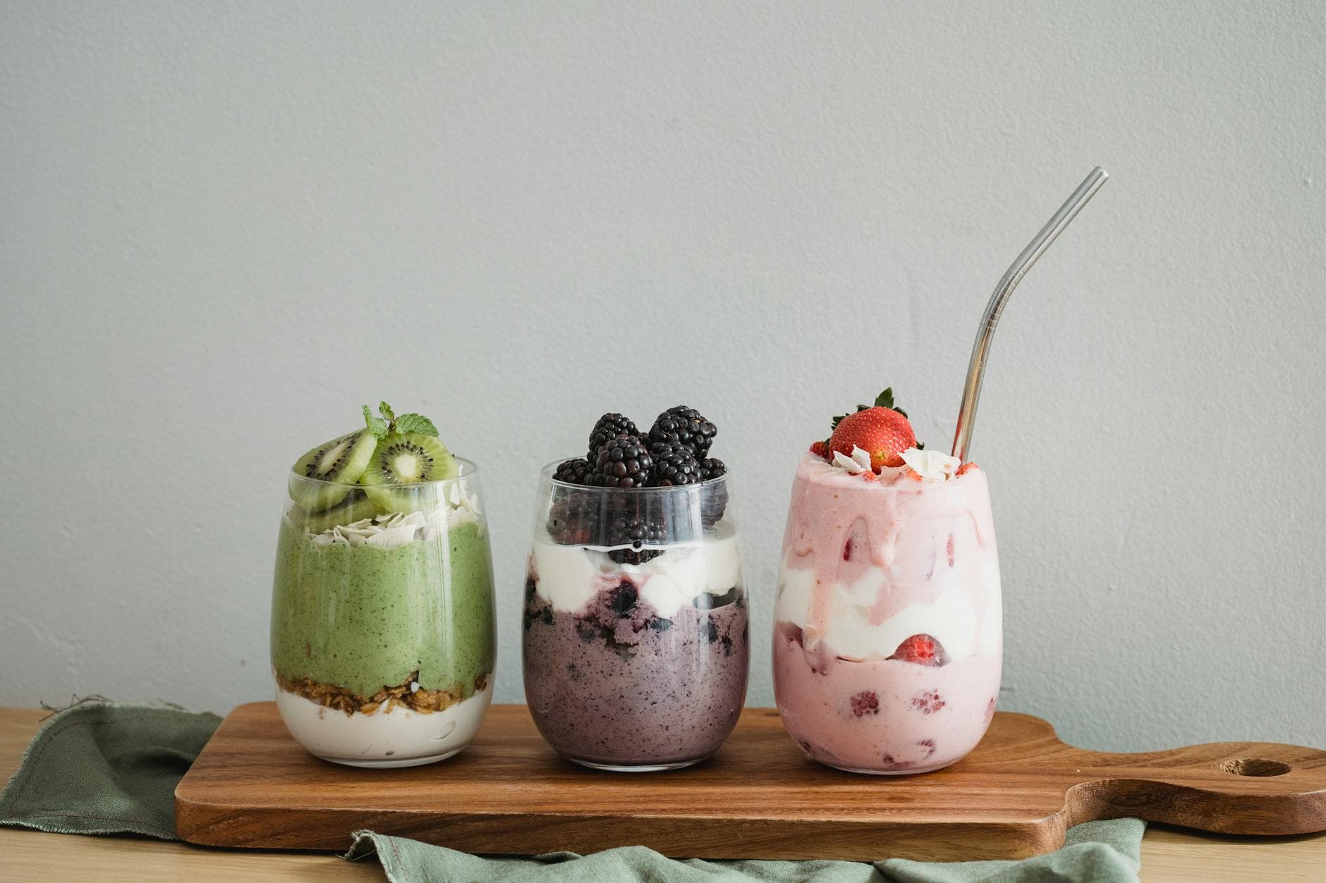 Colorful homemade fruit smoothies with kiwi, blackberry, and strawberry on a wooden board. - kid-friendly smoothie recipes