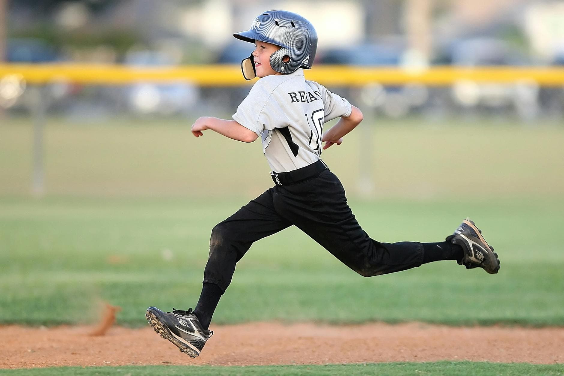 Action shot of a young baseball player running fast on the field, wearing uniform and helmet. - beginner running schedule