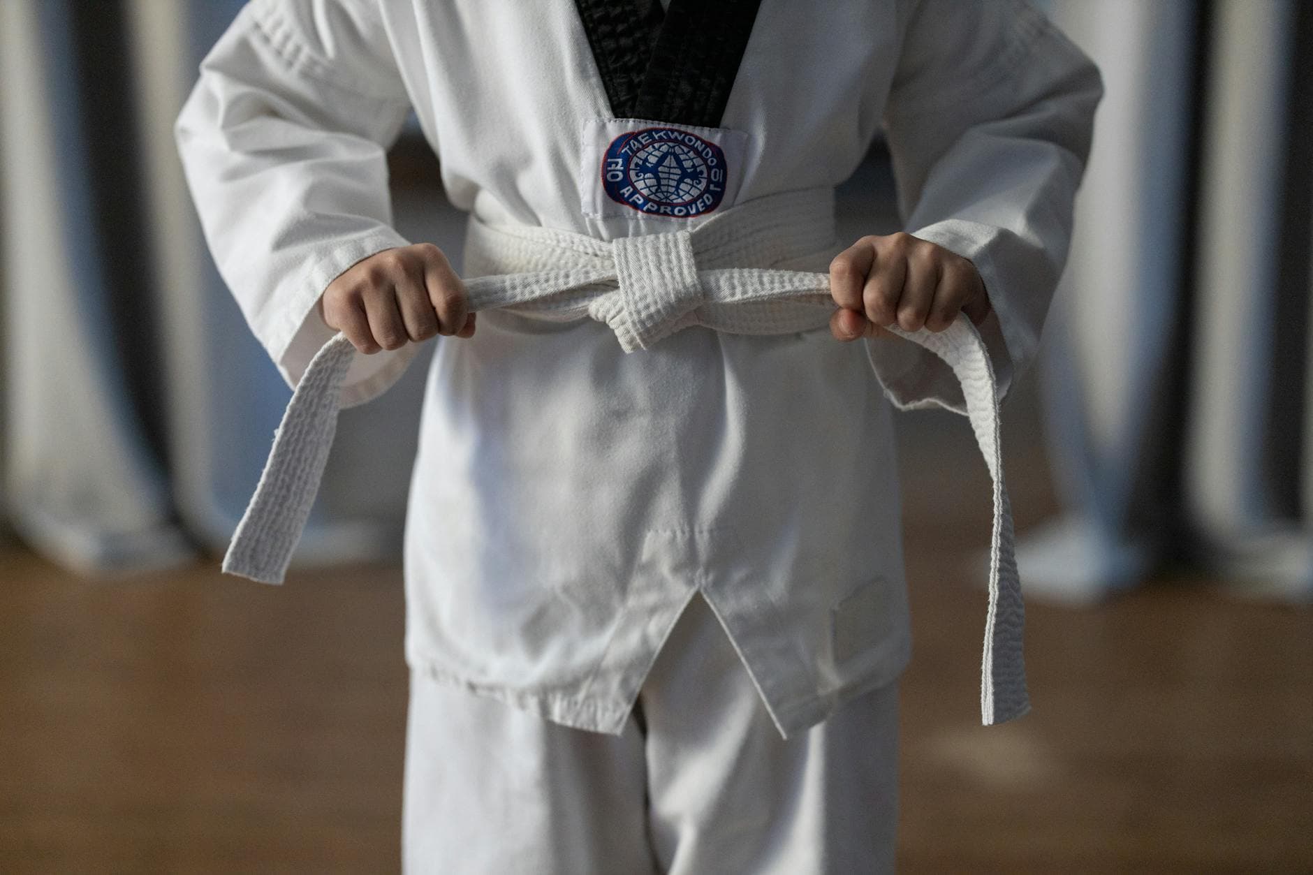 Close-up of a karate student tying a white belt in a traditional martial arts uniform. - beginner running tips