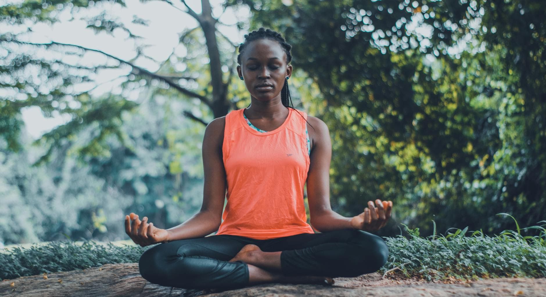 A woman meditating peacefully outdoors in a lush green setting, promoting relaxation and mindfulness. - breathing exercises stress