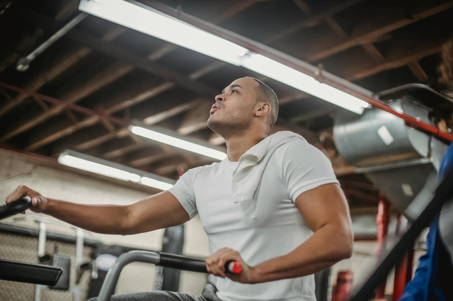 Focused man working out on a stationary bike in an indoor gym setting. - carb cycling workout