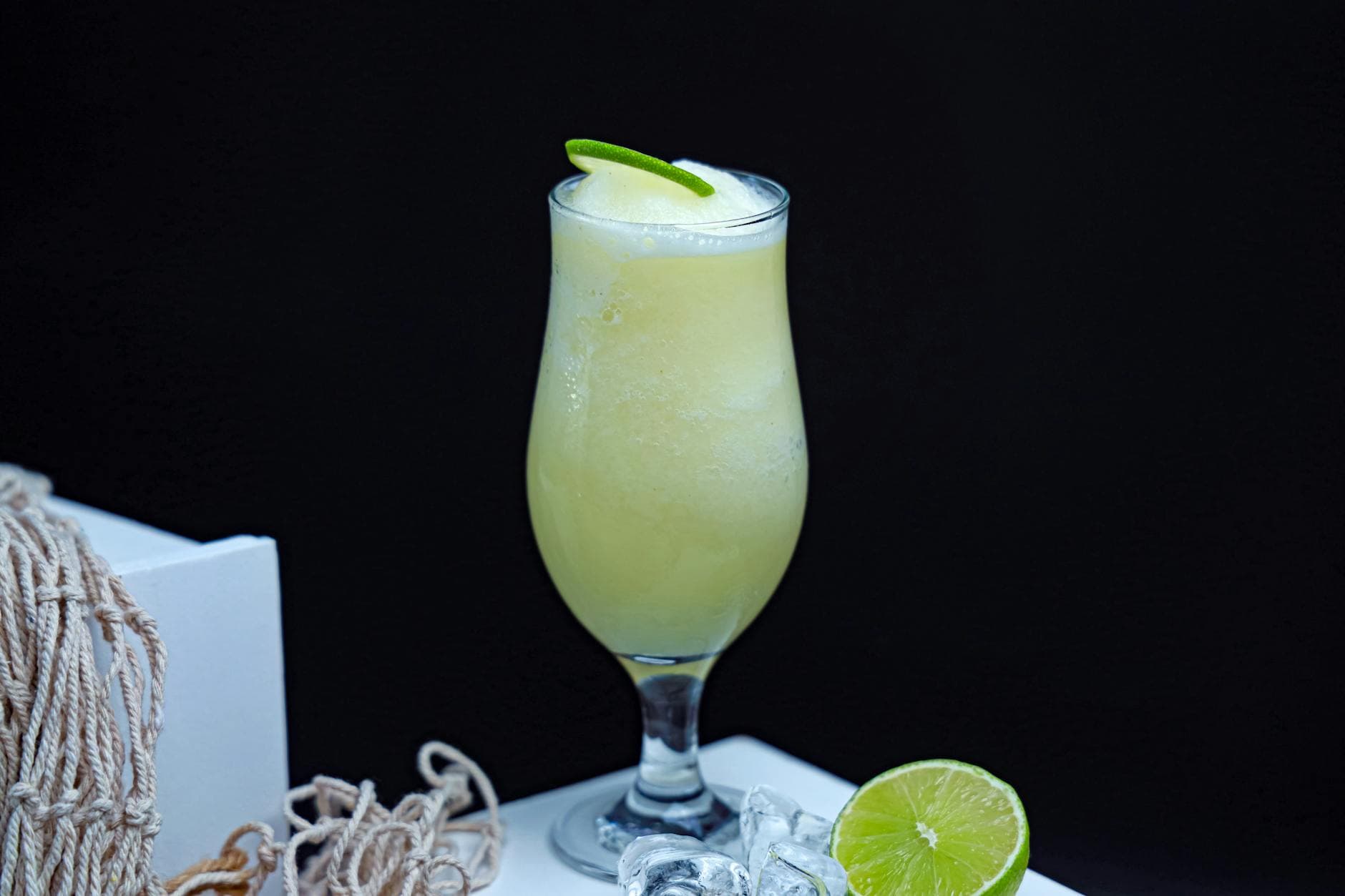 A refreshing lime smoothie in a glass with a lime garnish and ice cubes on the side. - detox smoothies