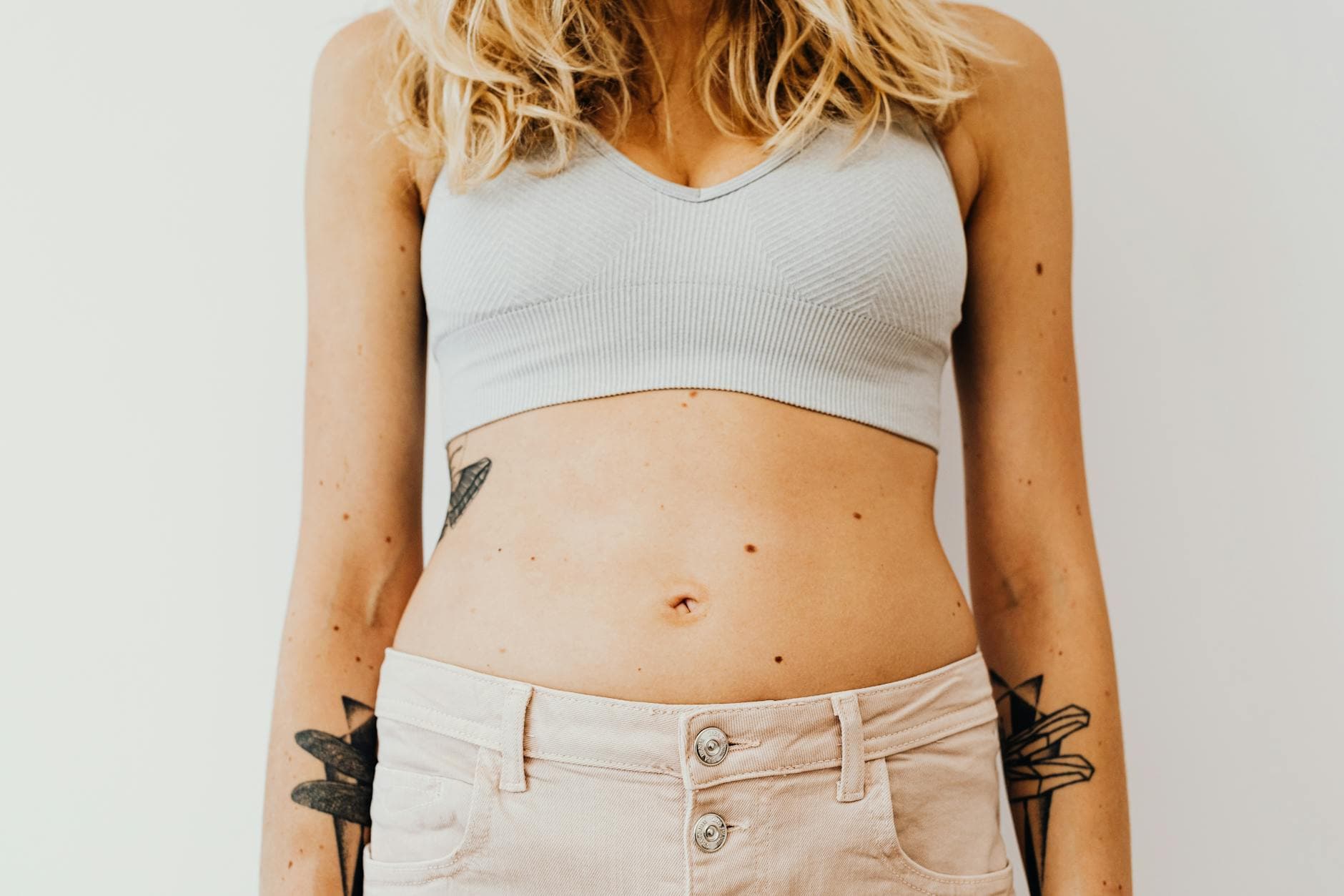 Close-up of a woman's midsection wearing a sports bra, showcasing tattoos and casual style. - easy weight loss