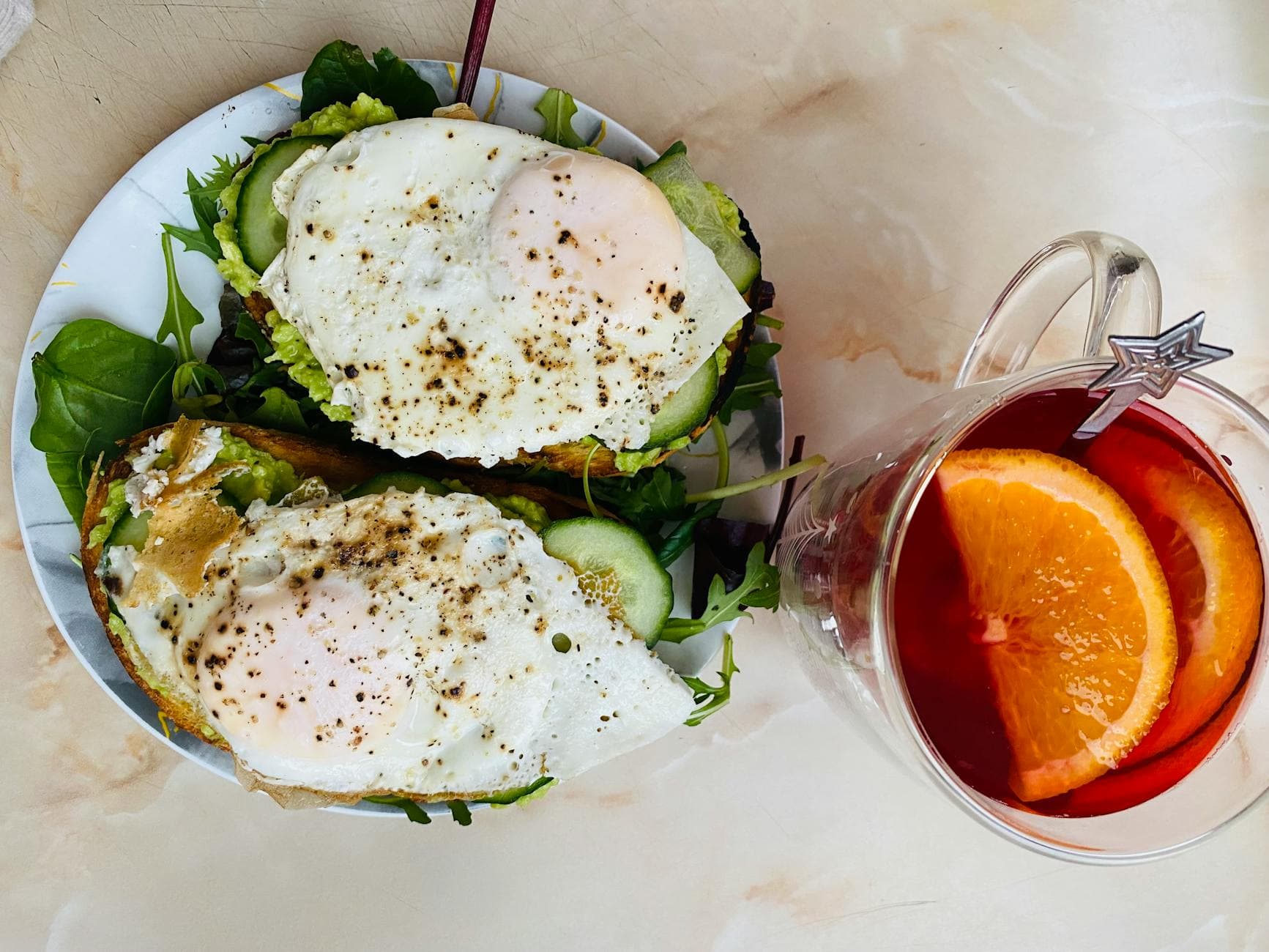 Delicious breakfast with avocado toast topped with eggs and herbal tea with orange slices. - spring meal prep