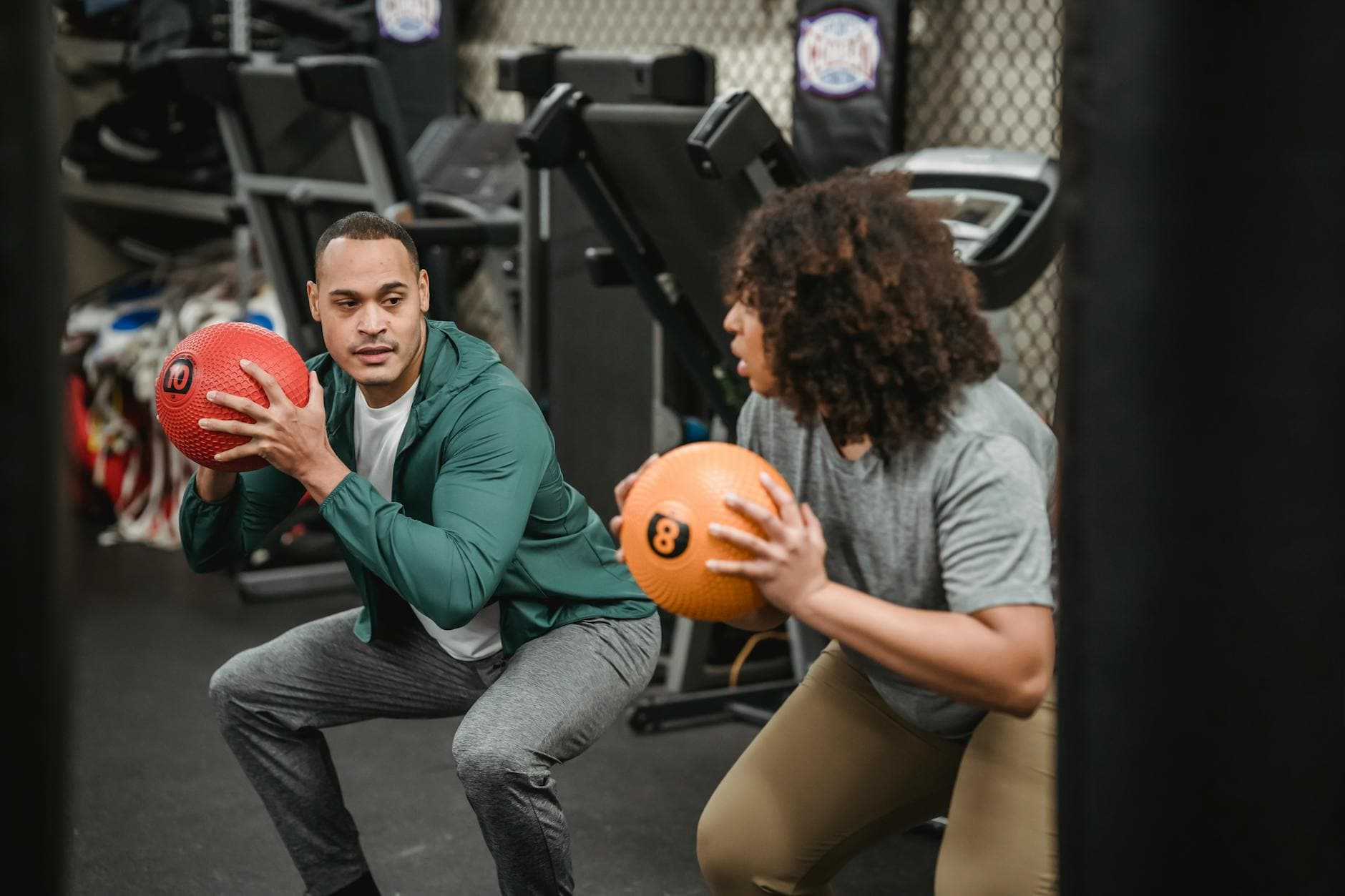 Two individuals performing squat exercises with medicine balls in a gym, emphasizing teamwork and fitness. - spring weight loss