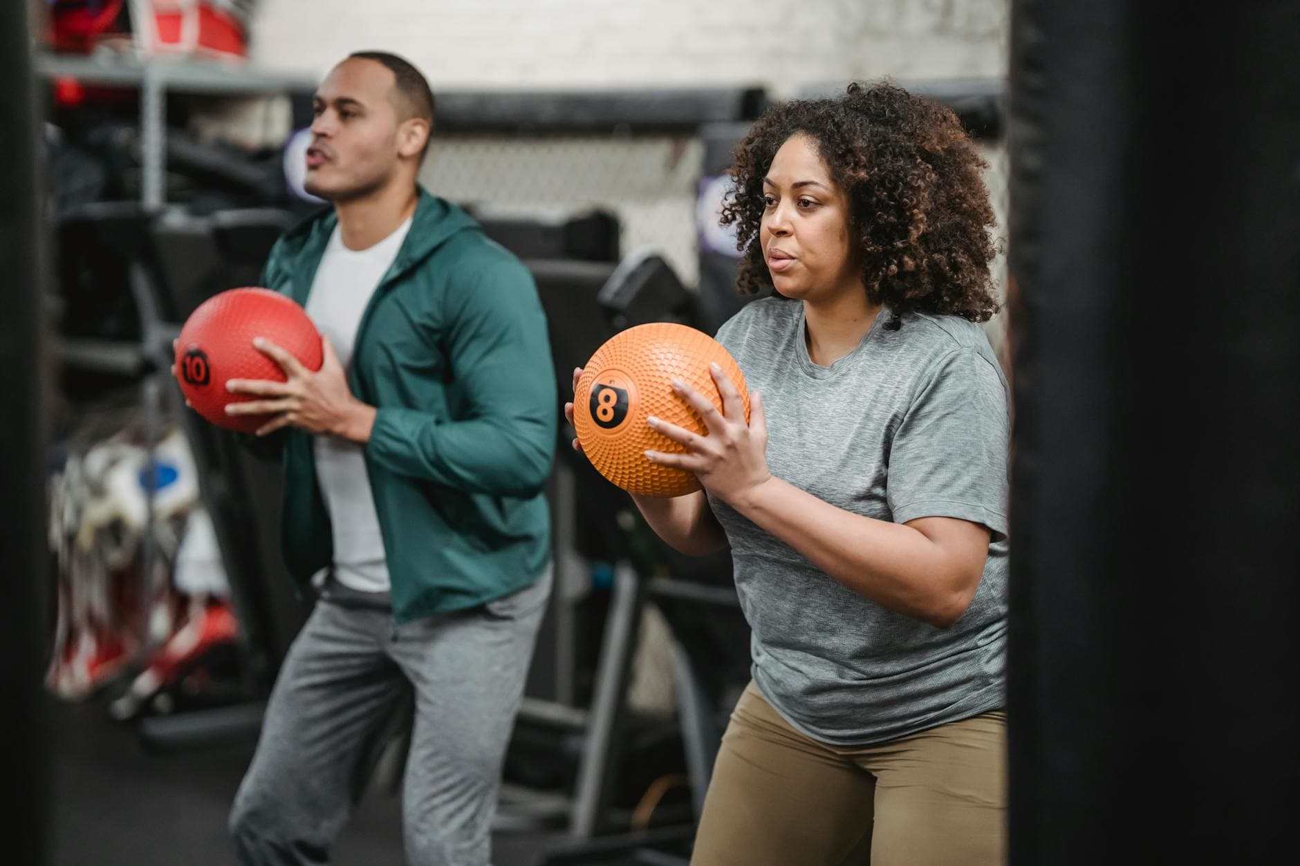Two adults engaging in a workout with medicine balls in an indoor gym setting. - weight loss myths