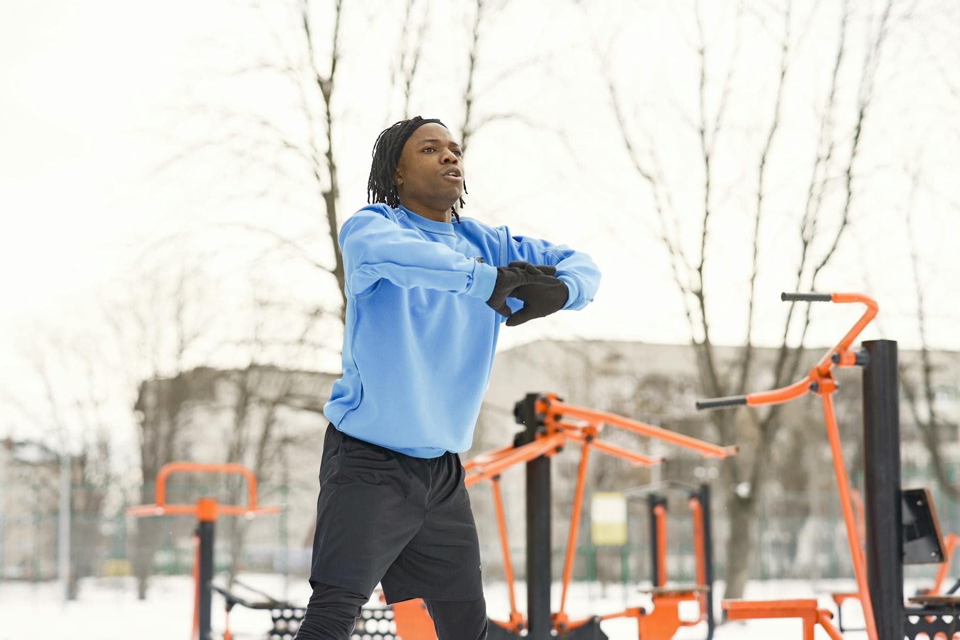 Athlete working out at an outdoor gym in wintertime, warming up in a blue sweatshirt. - winter wellness slump