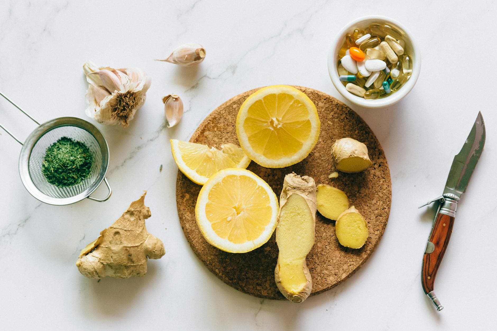 Flat lay of natural remedies including lemon, ginger, and garlic alongside pills. - anti-inflammatory foods