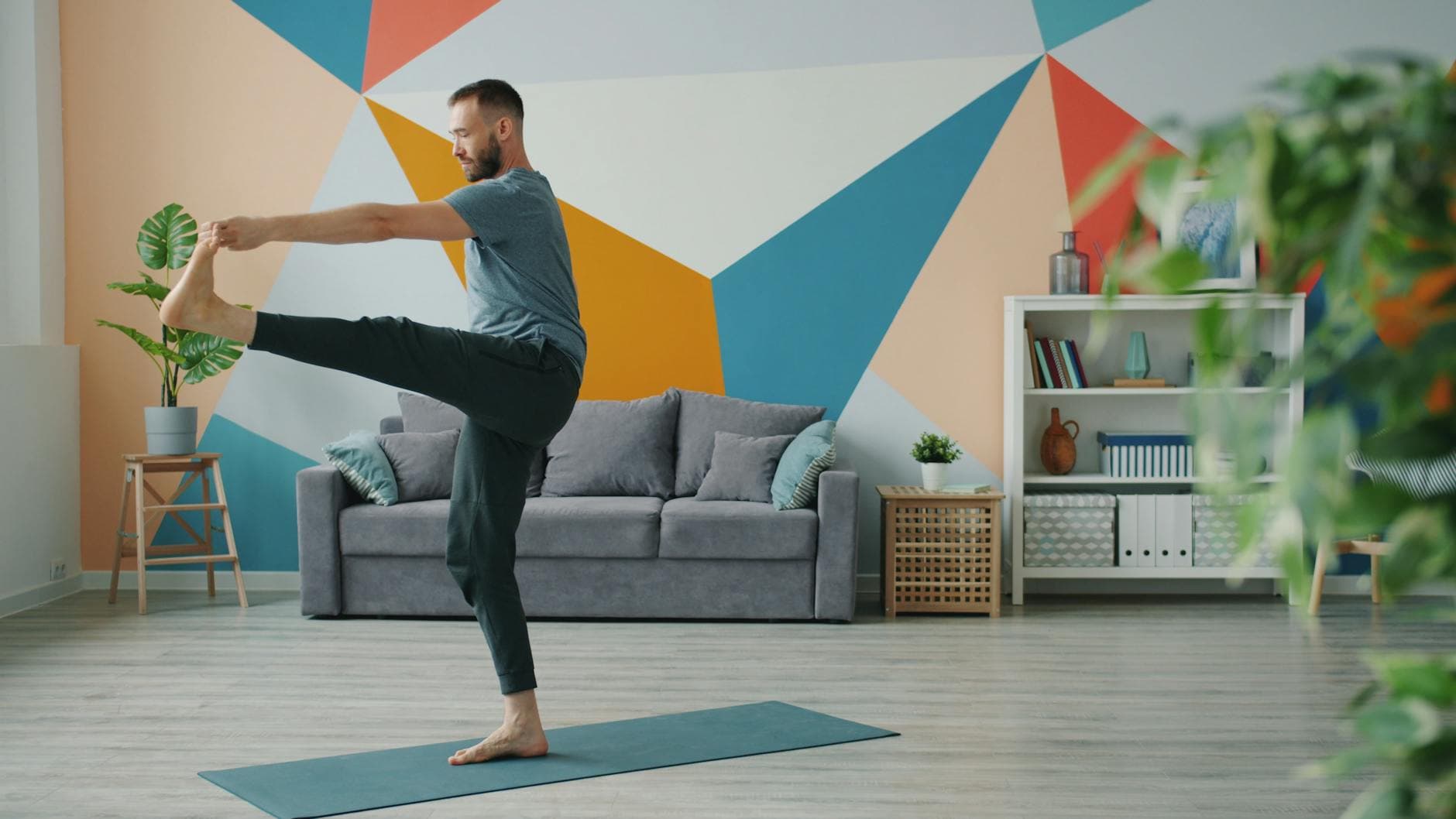 Man practicing yoga indoors with modern geometric wall art, maintaining balance and focus. - balance exercises