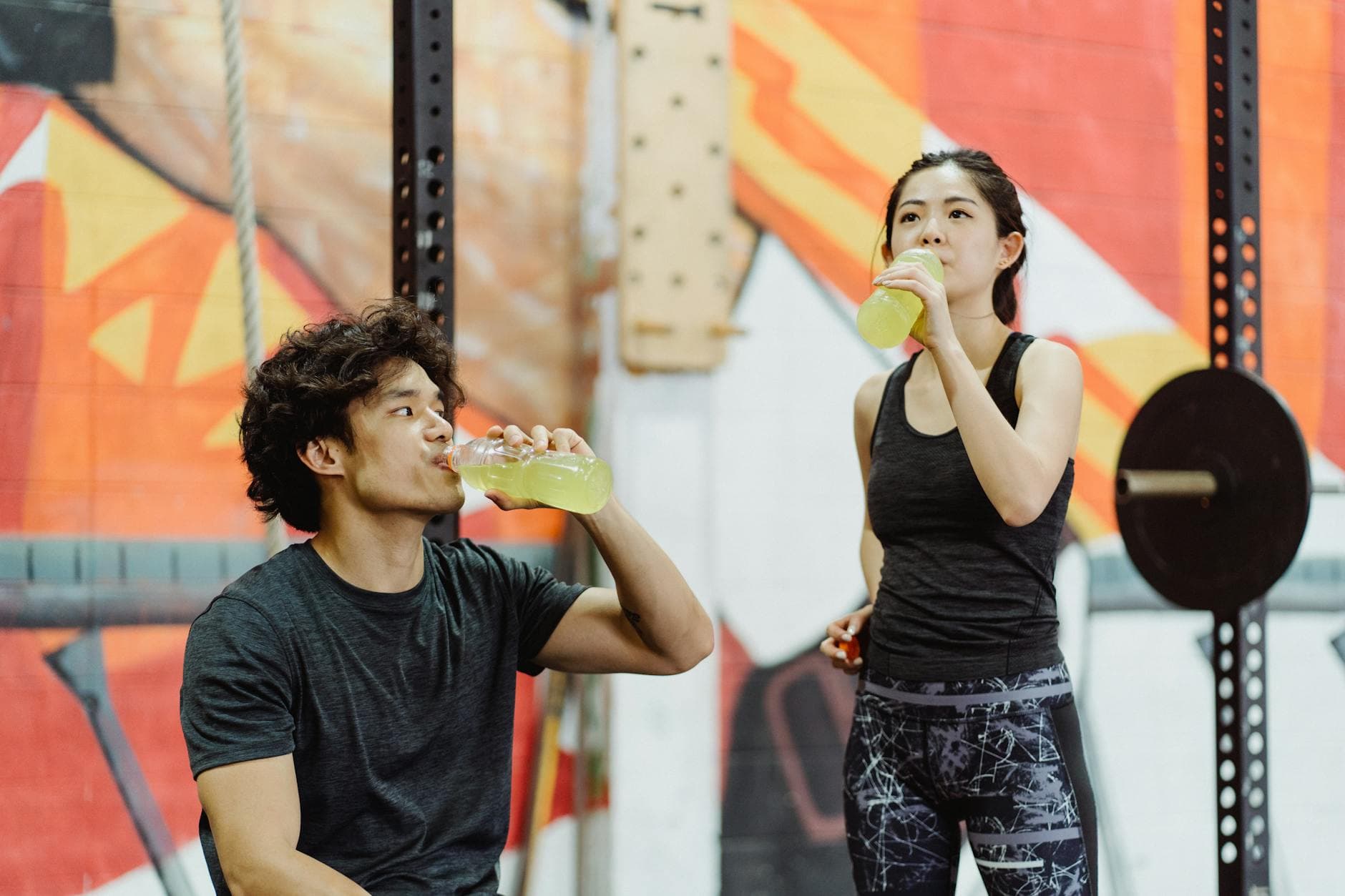 Couple in gym attire hydrating after a workout session indoors. - best recovery drink