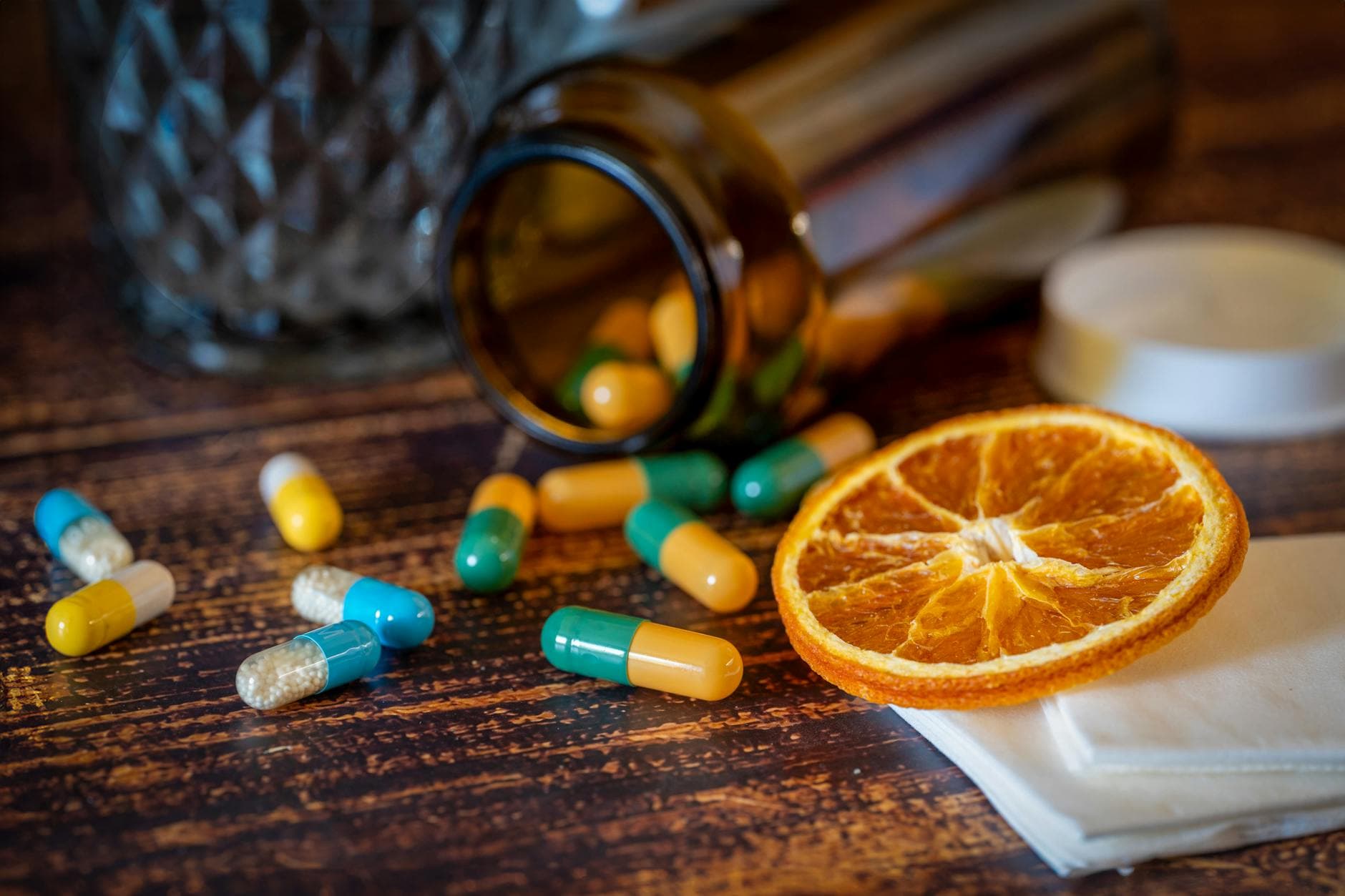 Close-up of vitamins, pills, and dried orange slice for cold relief. - boost immune system naturally