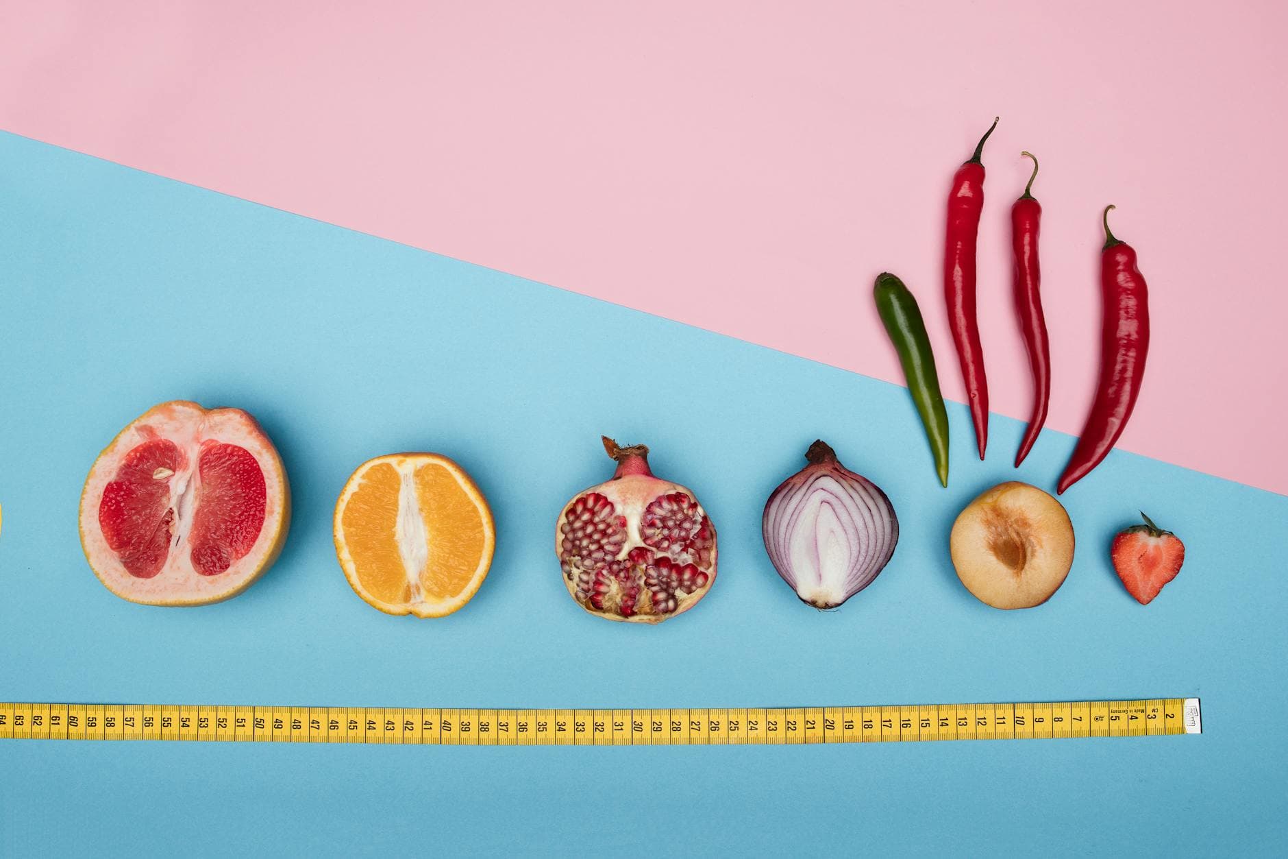 A vibrant flat lay of assorted fruits and vegetables with a tape measure on pastel pink and blue backgrounds. - boost metabolism naturally