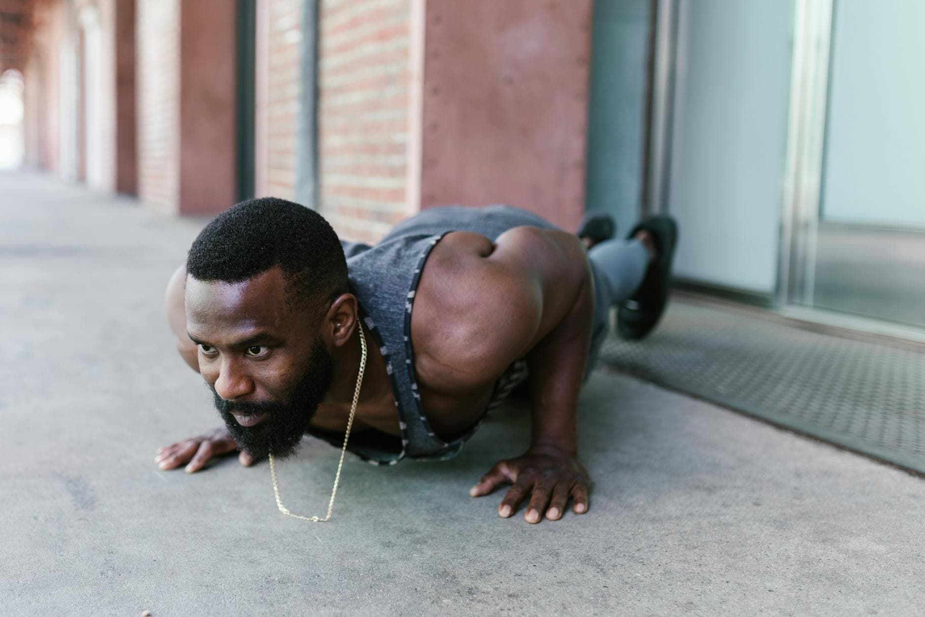 An athletic man exercises with a push-up in urban surroundings, showcasing strength and fitness. - no equipment workouts