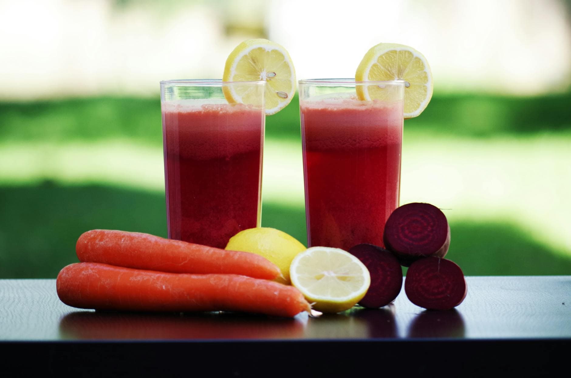 Colorful glasses of beetroot and carrot juice garnished with lemon slices, symbolizing health and freshness. - gentle spring detox