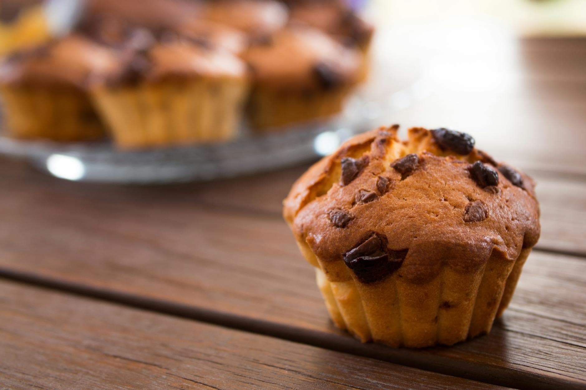 A close-up view of a chocolate chip muffin on a wooden table, perfect for food blogs. - healthy breakfast muffins