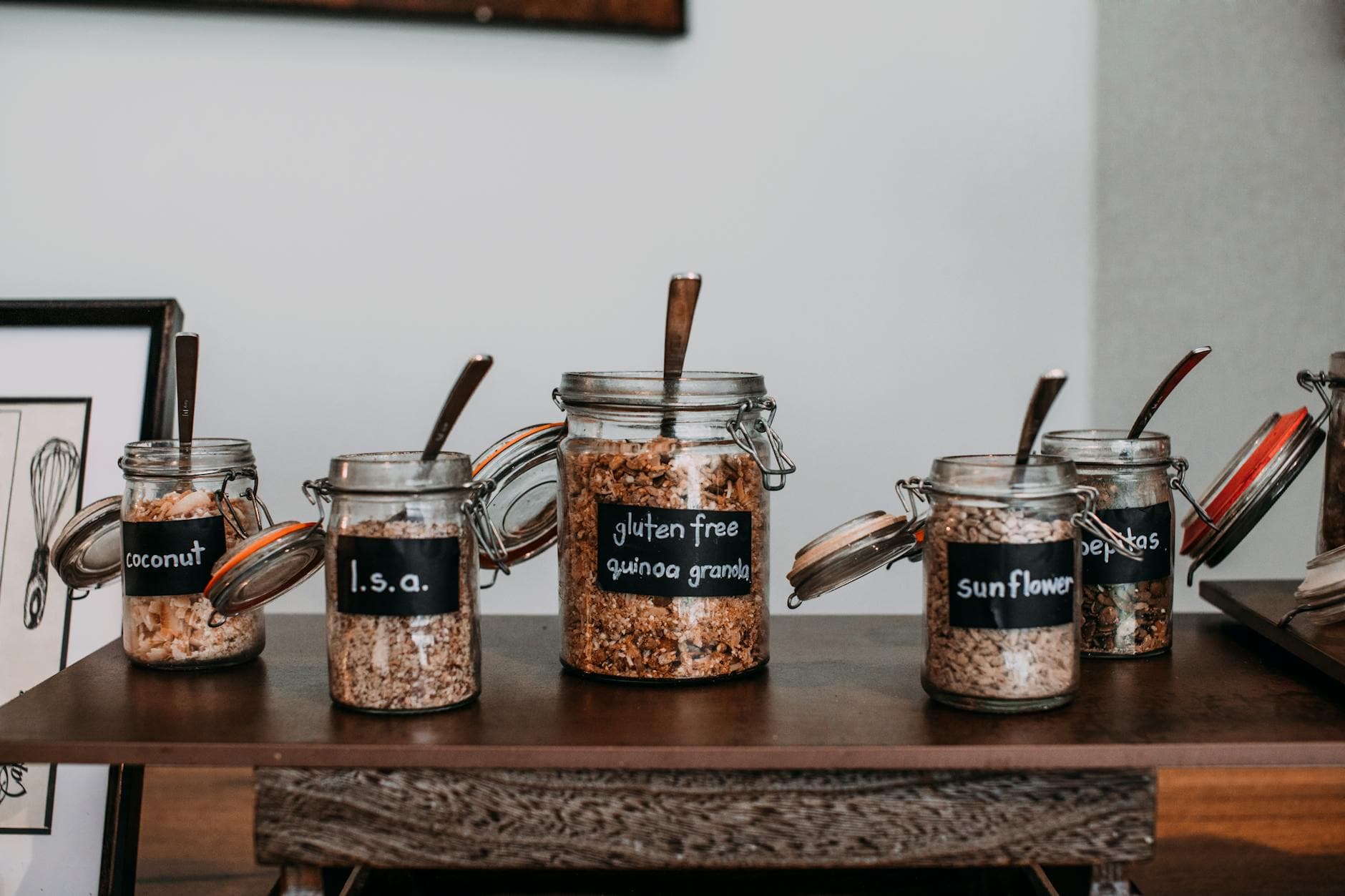Close-up of labeled glass jars containing various grains and seeds on a wooden table. - pantry cleanout weight loss