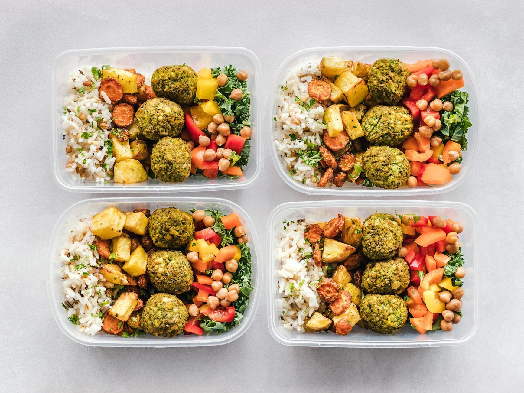 Colorful meal prep containers with falafel, chickpeas, rice, and vegetables for a healthy lifestyle. - quick lunch recipes