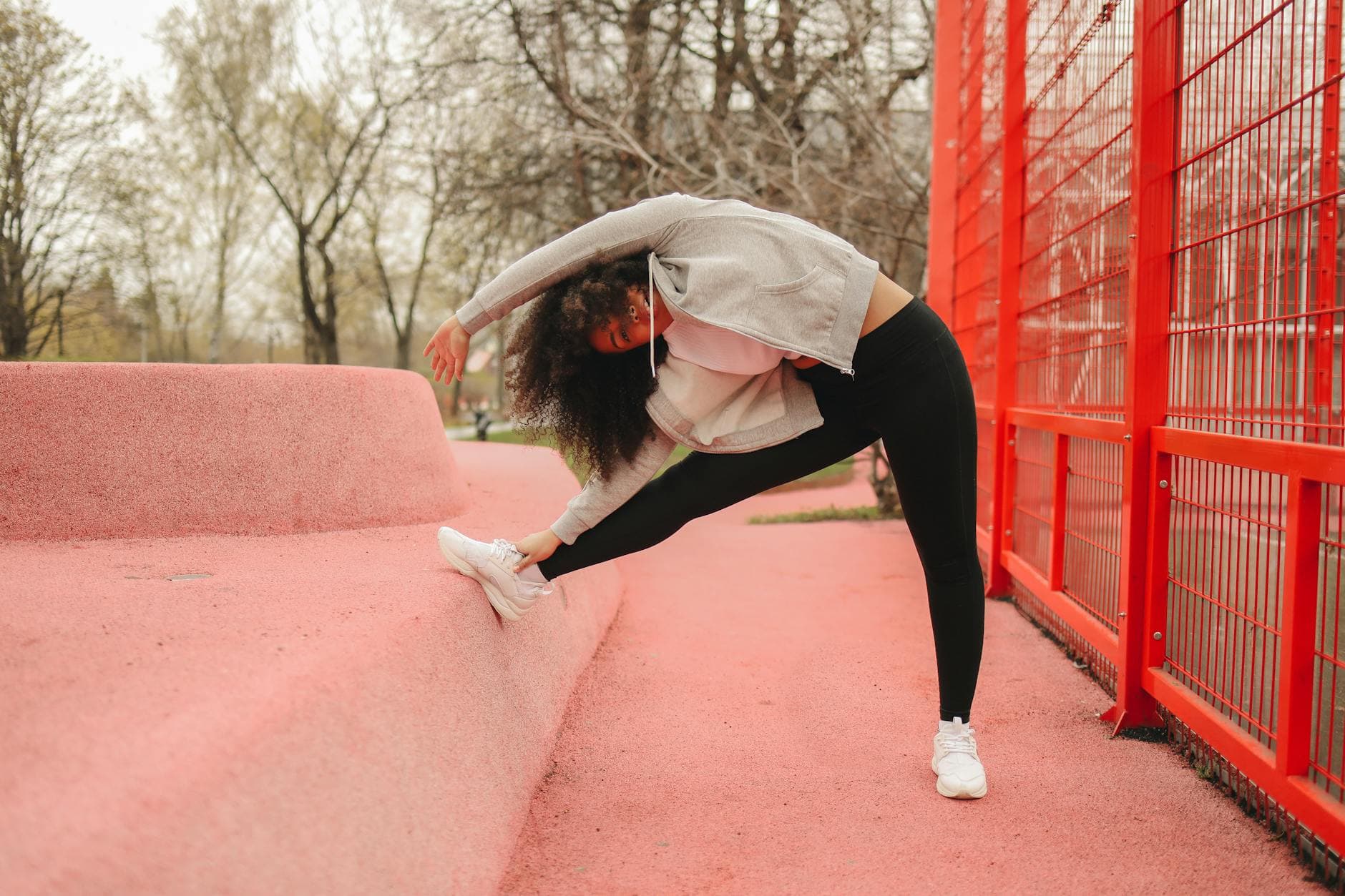 Woman stretching outdoors against a bright red structure, promoting fitness and wellness. - spring allergies exercise