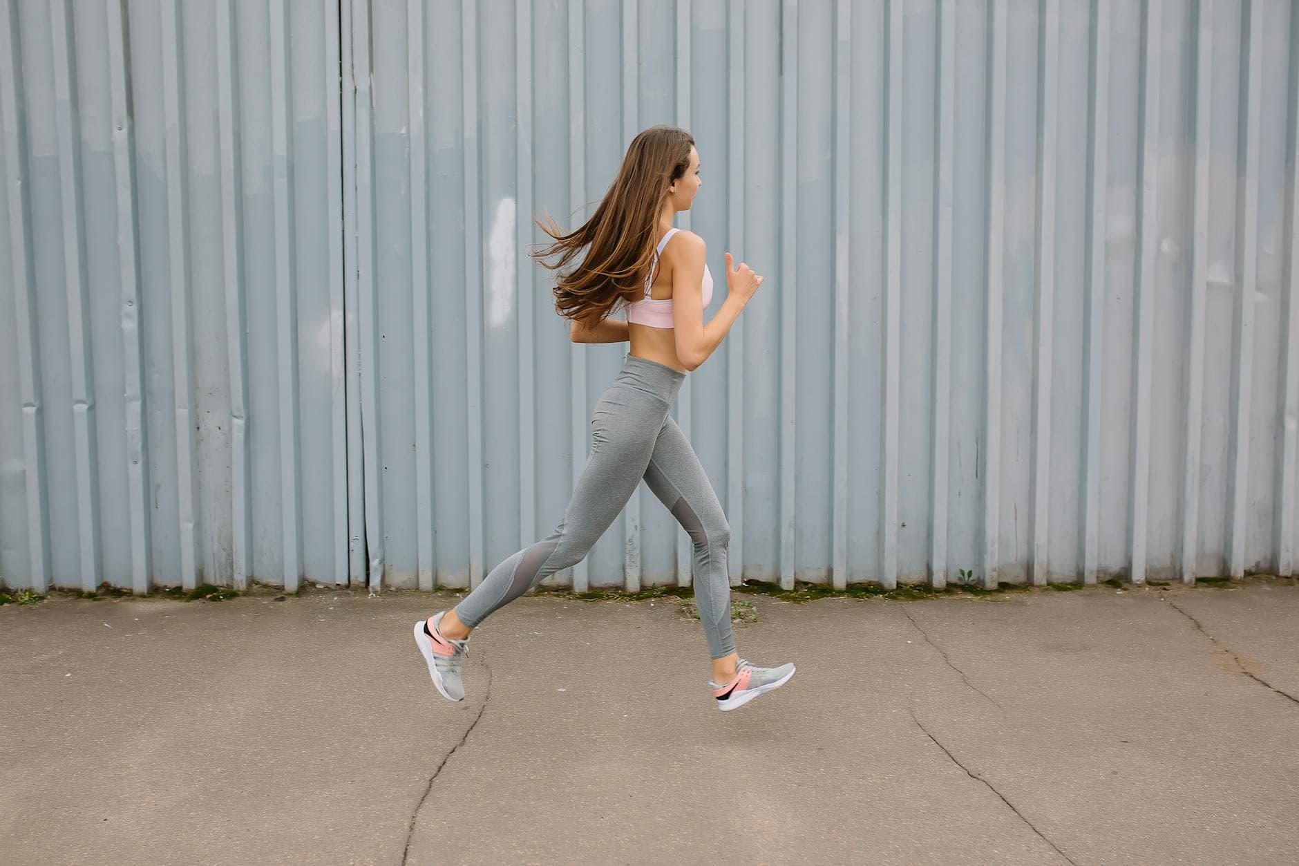 Fit woman running outdoors in activewear with sports bra and leggings. Motion captured at day time. - spring running for beginners