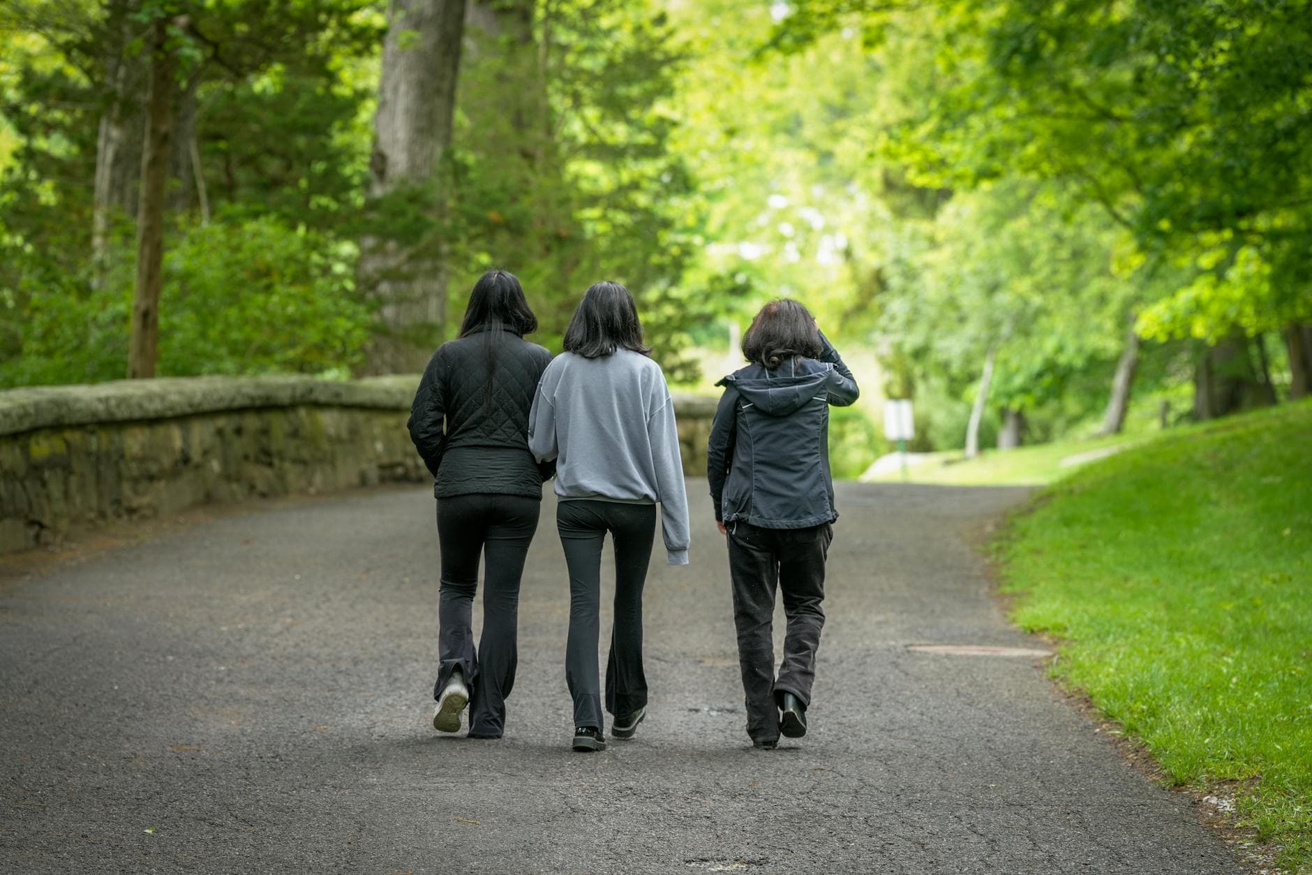 Three people walk together on a scenic path in Darien, Connecticut, surrounded by lush greenery. - spring walking plan