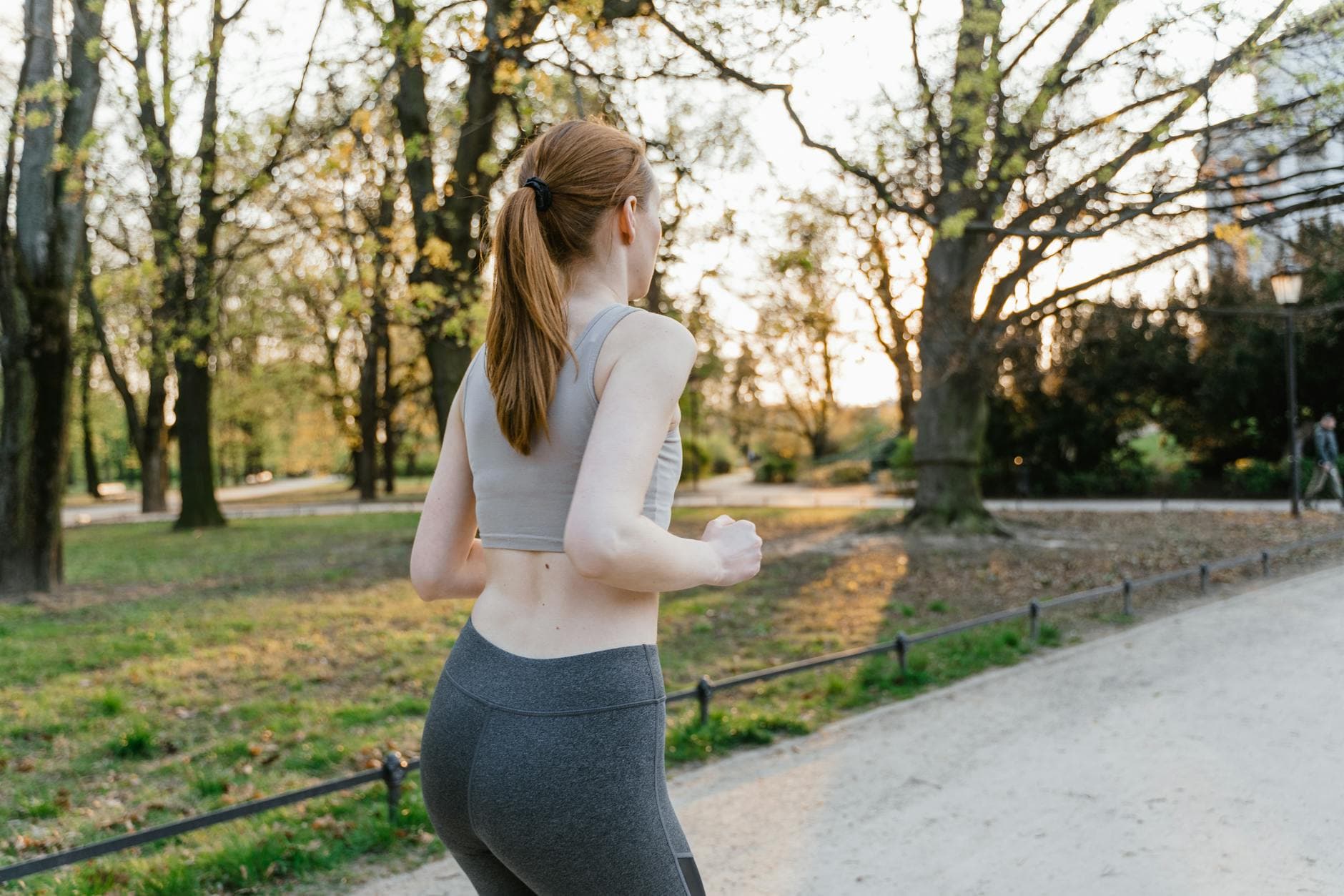 A woman jogs in a park during sunset, enjoying an outdoor fitness routine. - spring workouts busy mornings