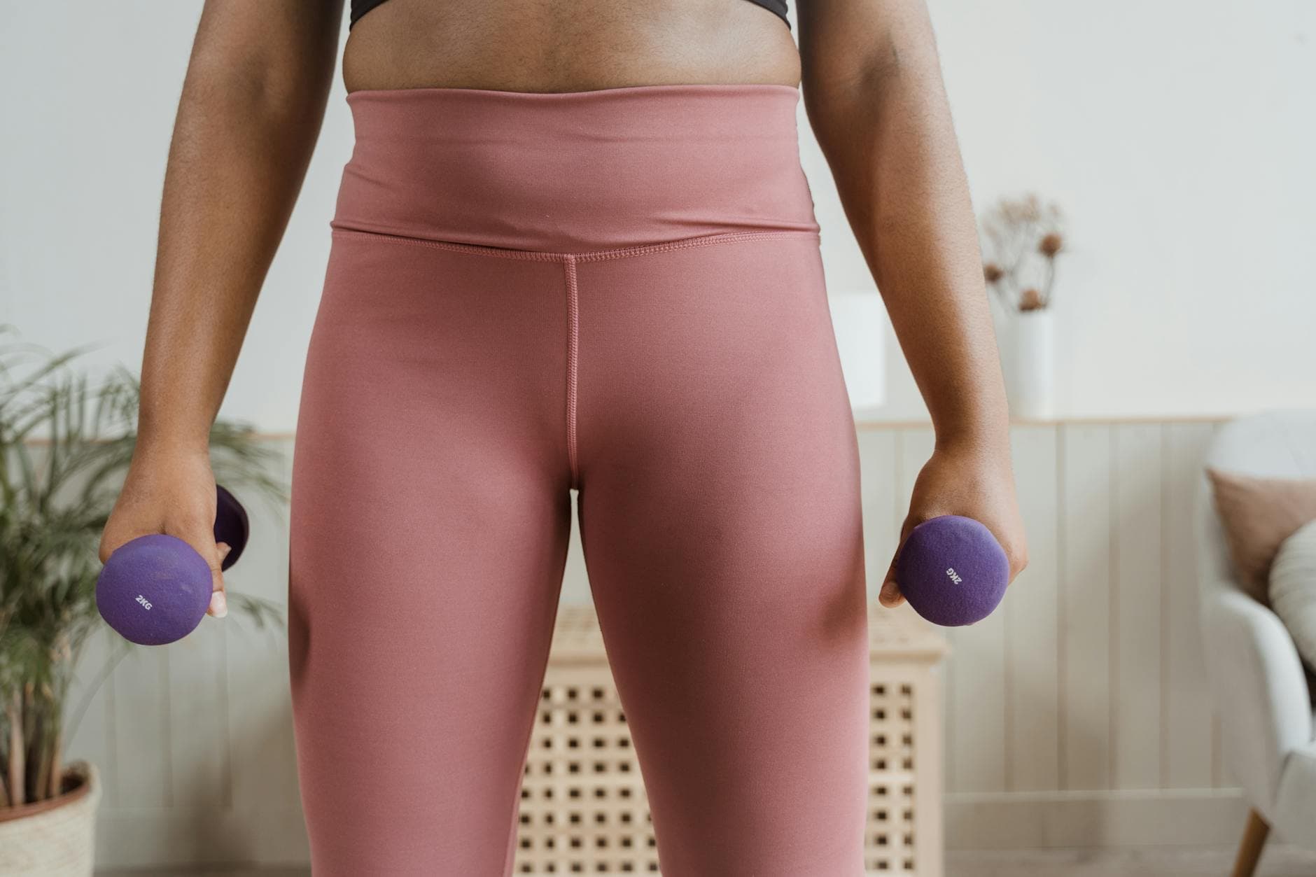 Close-up of a woman holding purple dumbbells, highlighting fitness and healthy lifestyle indoors. - strength training for women