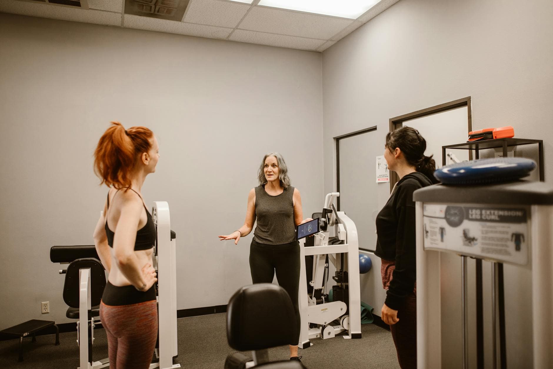 Three women discuss fitness and wellness in a gym setting, promoting healthy living. - weight loss for women