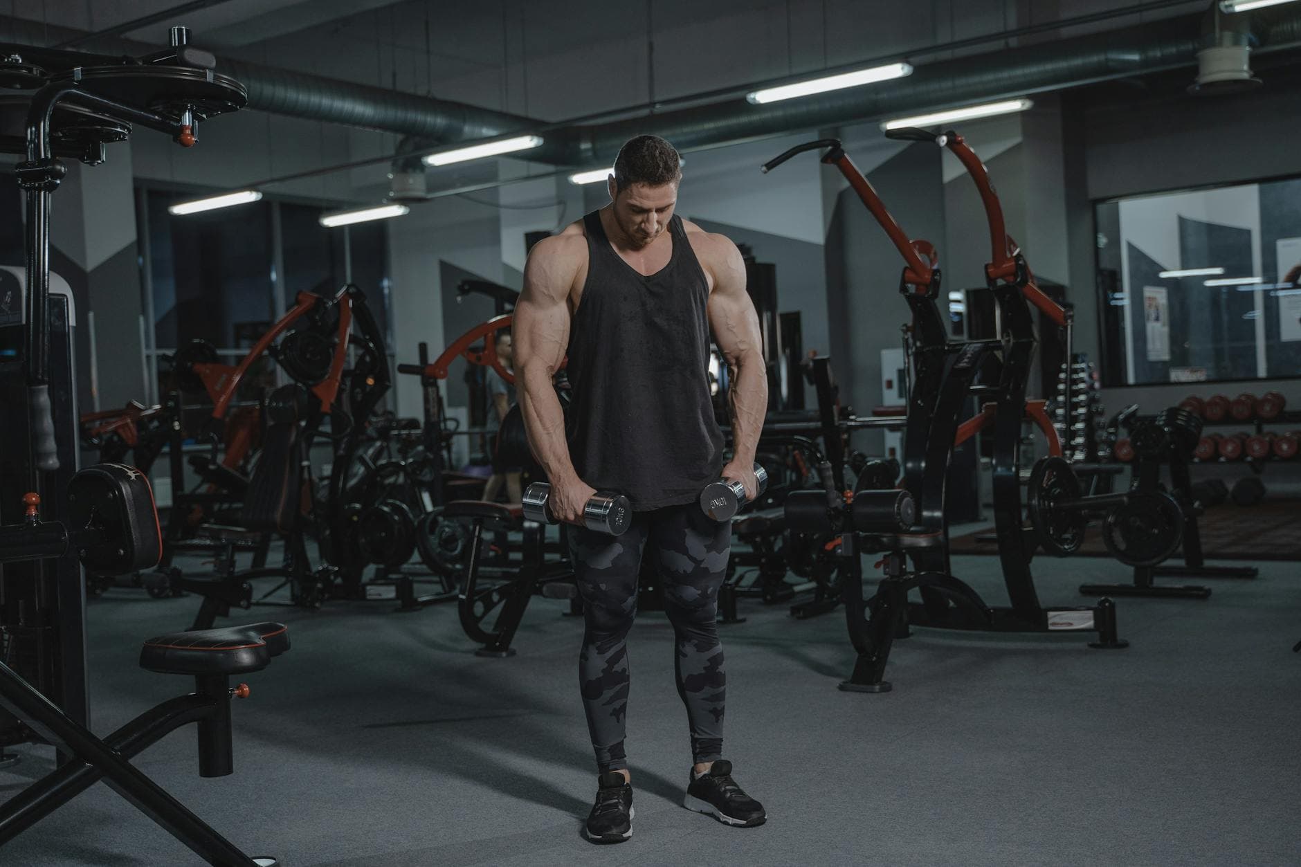 Muscular man lifting dumbbells in a modern gym setting, demonstrating strength and fitness. - weight training benefits