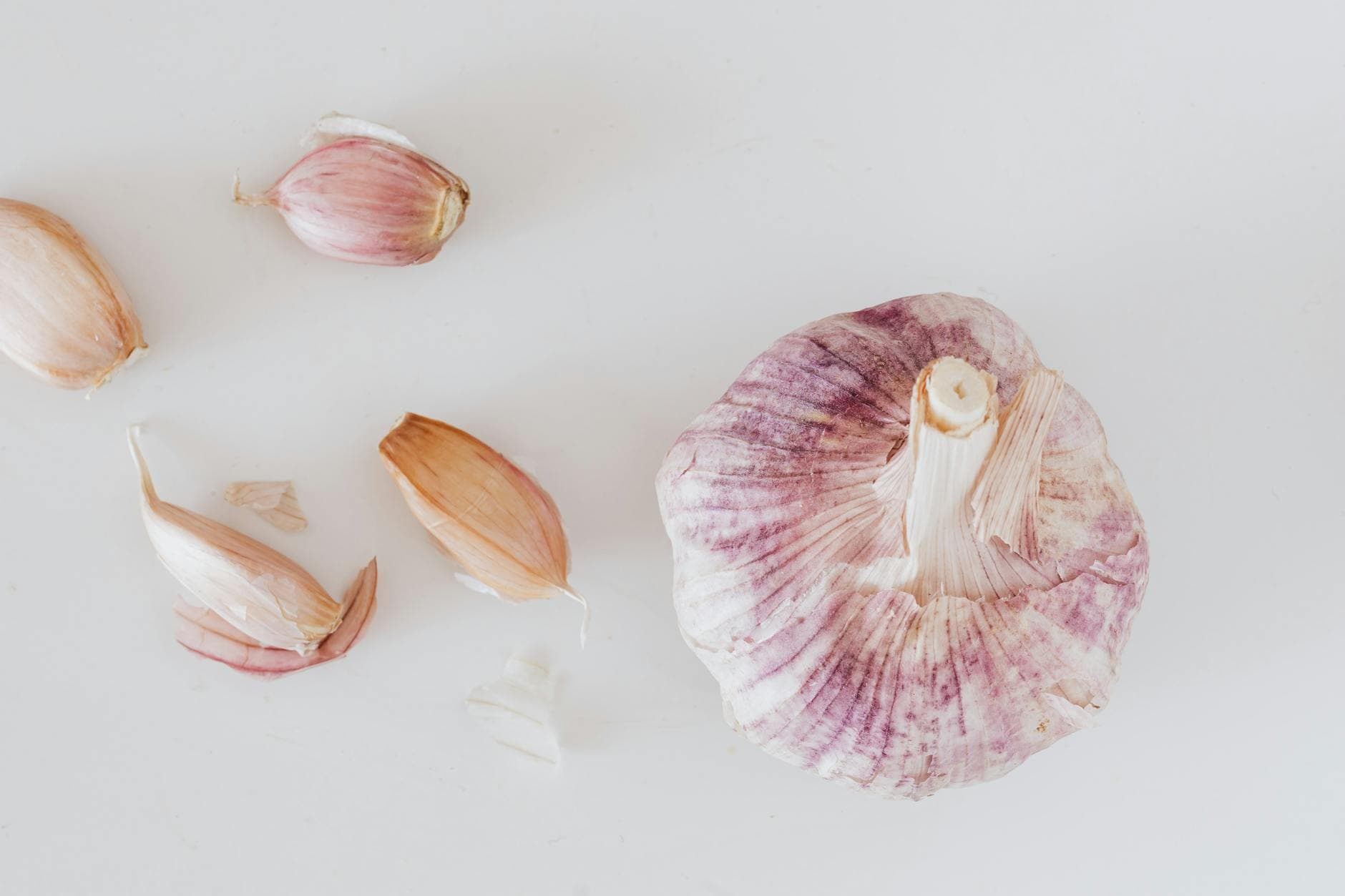 From above closeup of big whole garlic and set of cloves placed on white surface - anti-inflammatory foods spring allergies