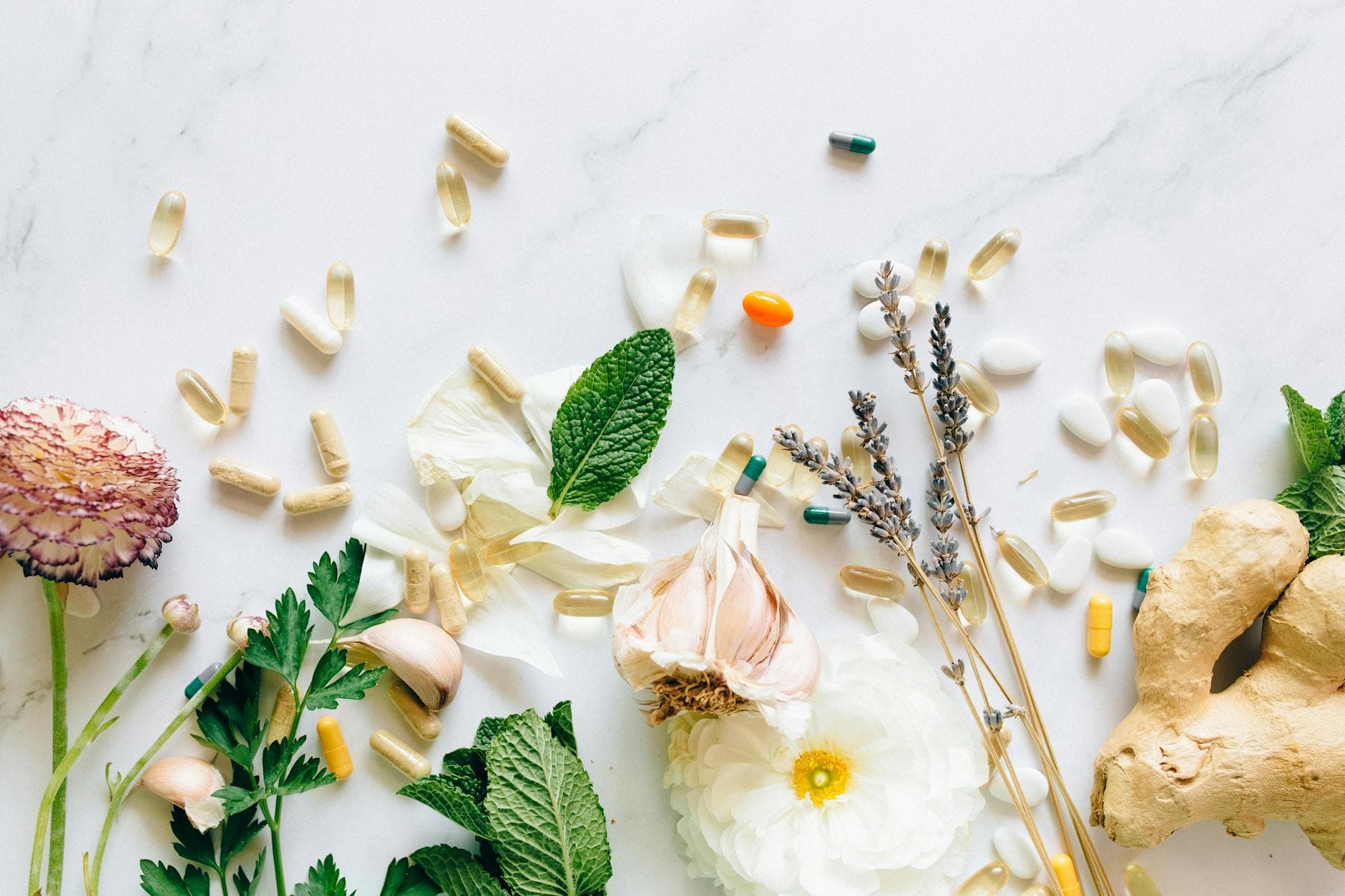 A flatlay of natural herbs, supplements, and flowers on a marble background. - boost immunity naturally