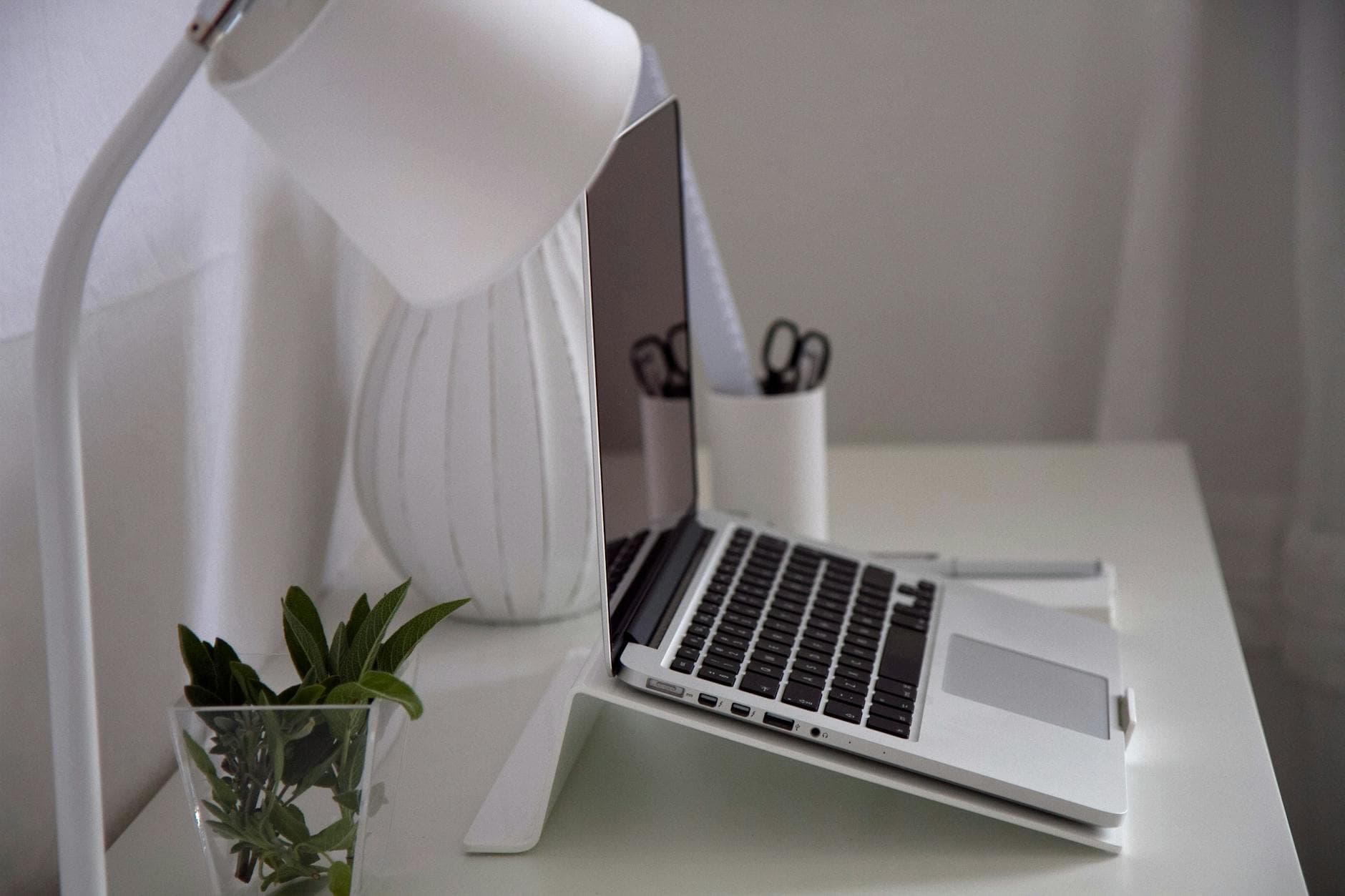 Modern home office with a laptop, desk lamp, and plant on a white desk. - desk exercises