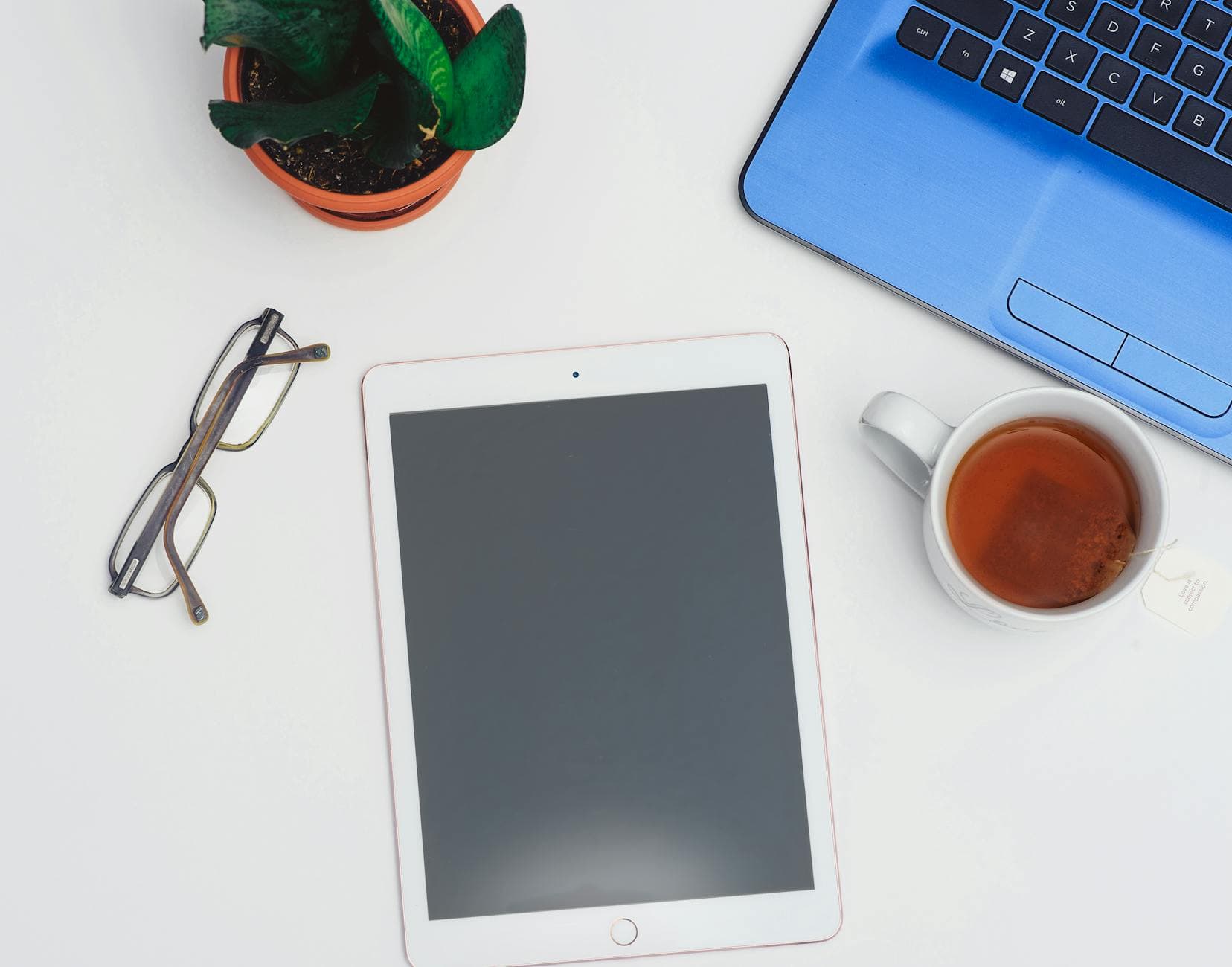 A modern workspace setup featuring a tablet, laptop, and a cup of tea for productive work sessions. - digital declutter spring