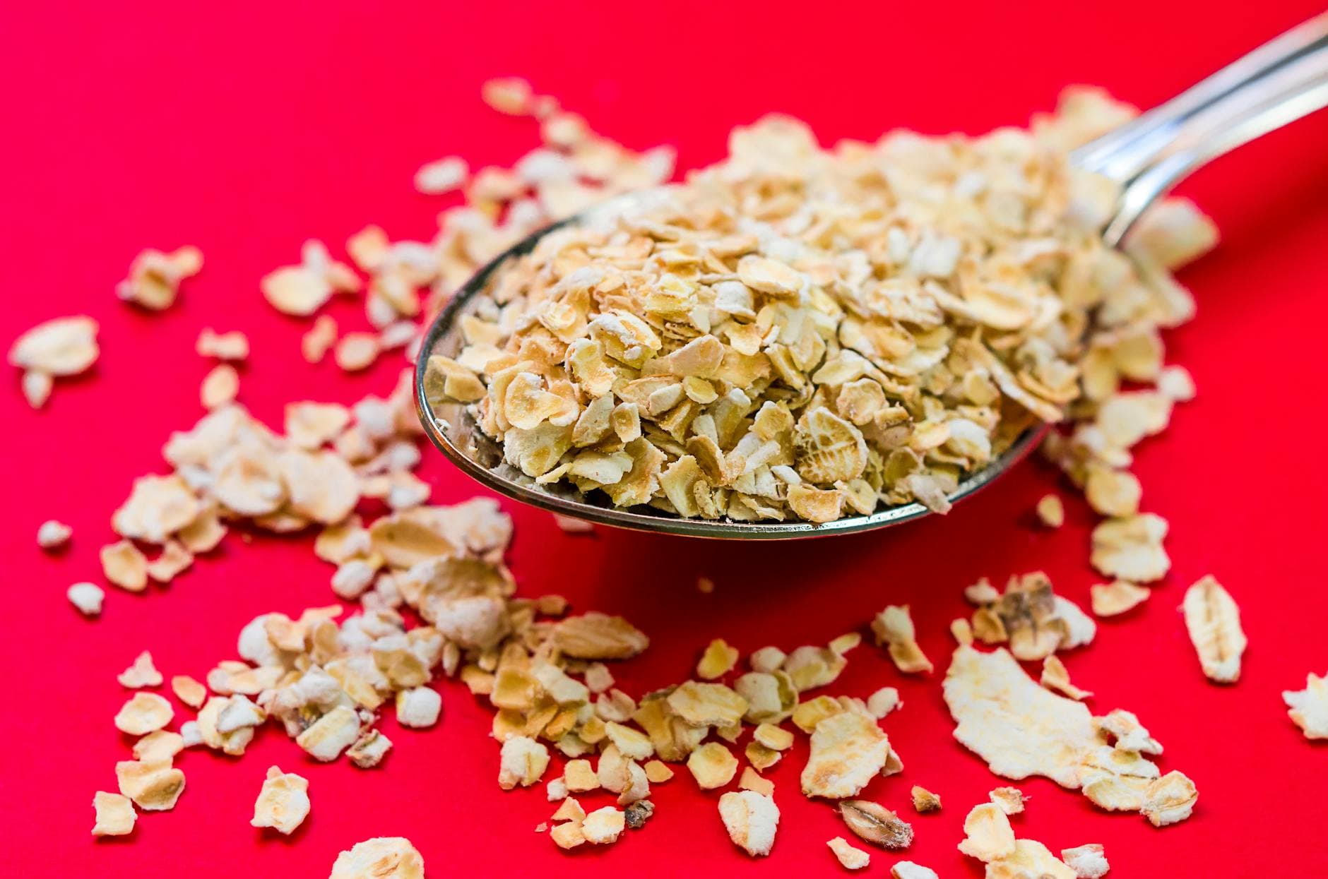 Close-up image of oats scattered on a spoon with vivid red background, perfect for food advertising. - fiber foods fullness