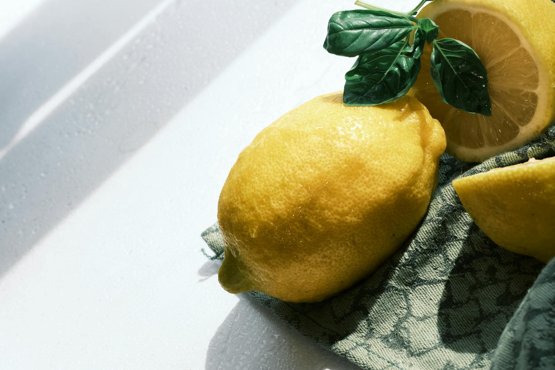 Bright lemons with basil leaves on a sunlit surface perfect for summer themes. - glowing skin foods
