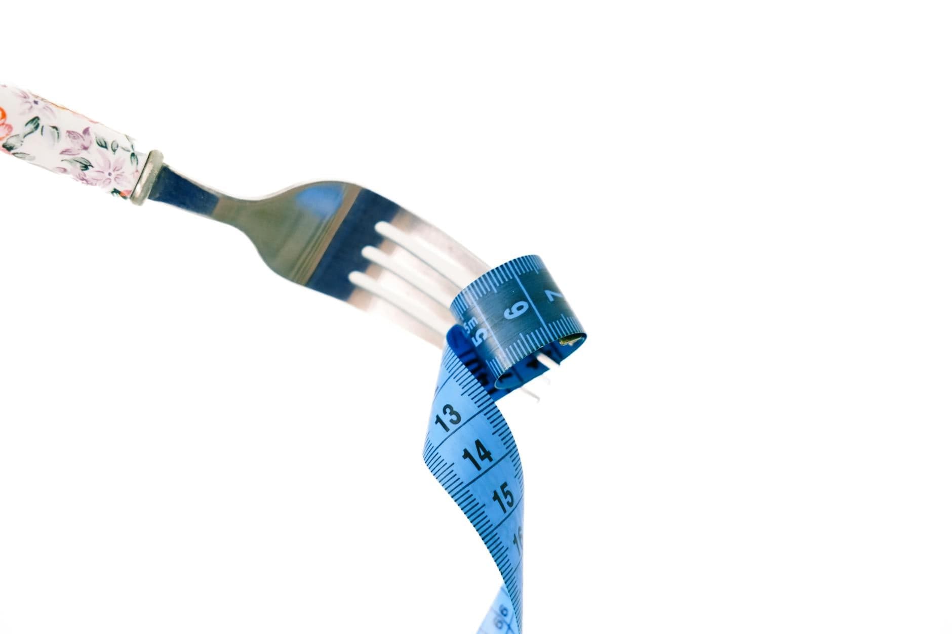 A fork twirls a blue measuring tape, symbolizing weight management and health. - healthy weight loss