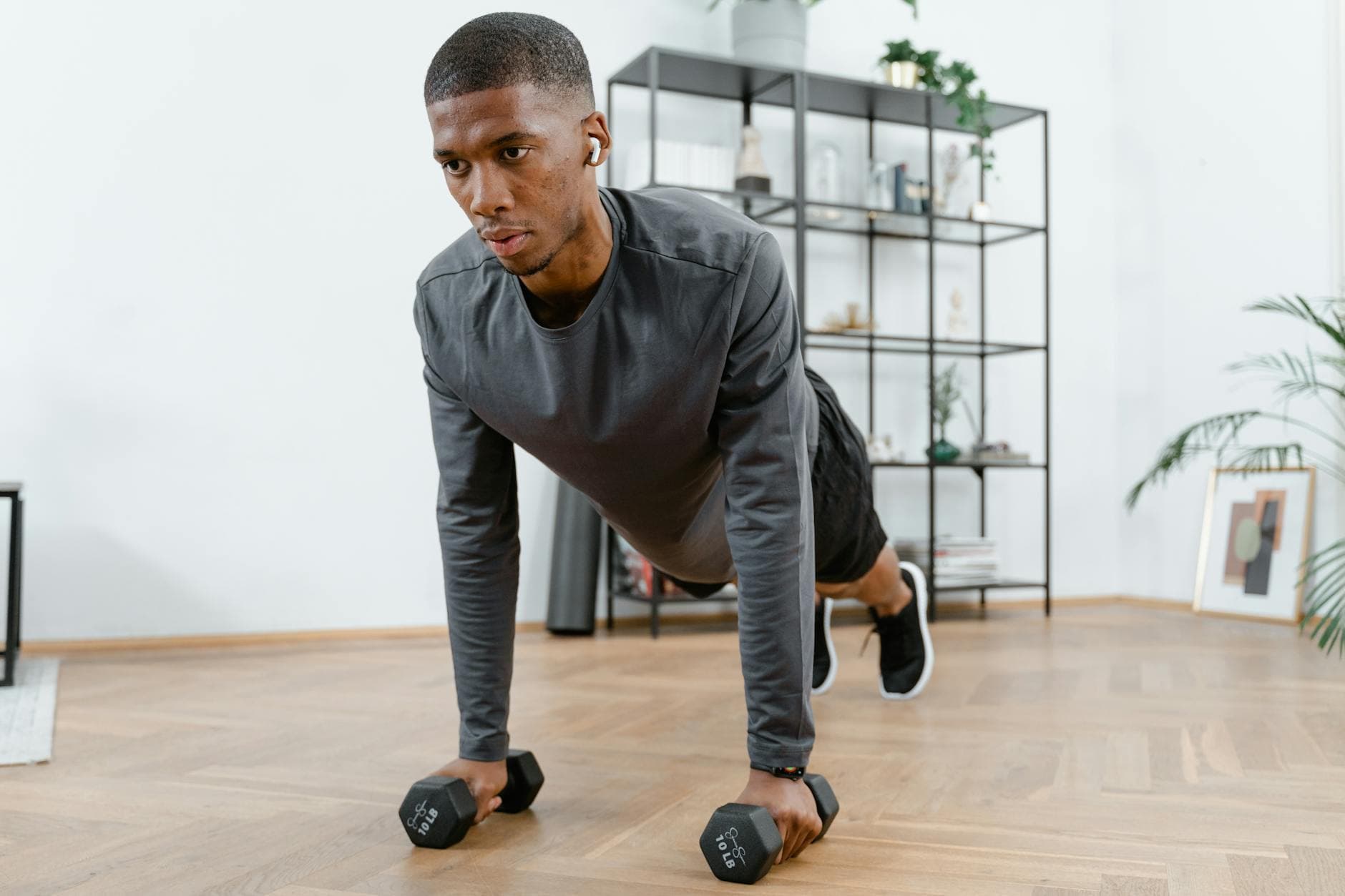 Man performing push-up exercises with dumbbells indoors. Fitness and healthy lifestyle concept. - hiit fat burning