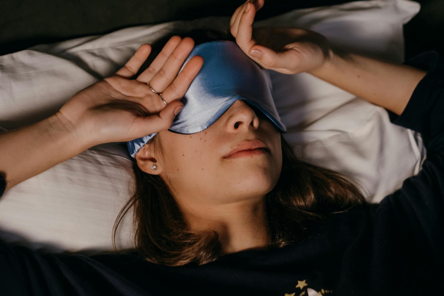 A woman peacefully resting with a sleep mask in a cozy indoor setting. - improve sleep quality