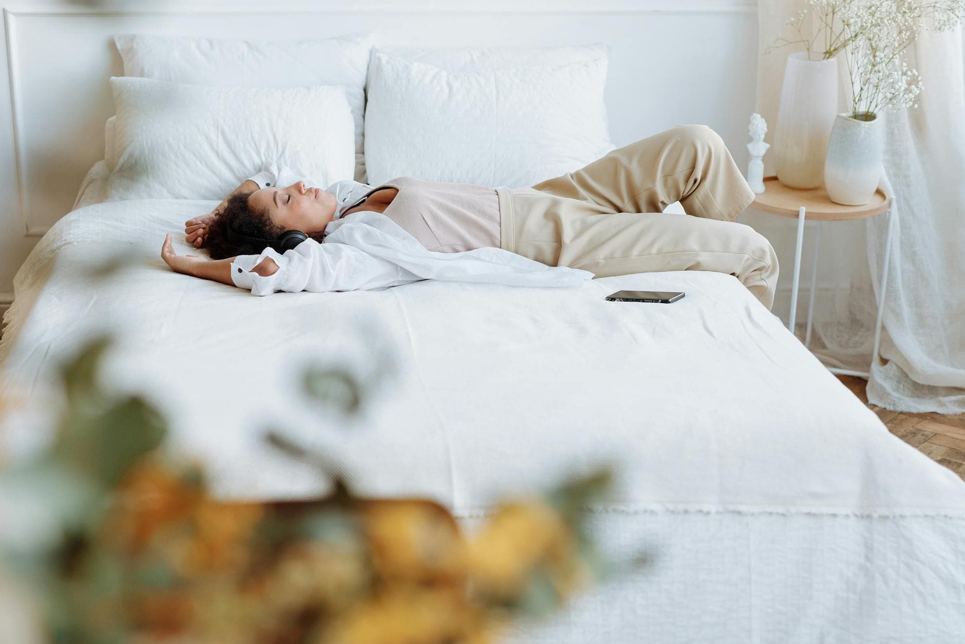 A woman enjoys a peaceful moment lying on a comfortable bed in a bright, cozy bedroom. - restful bedroom environment