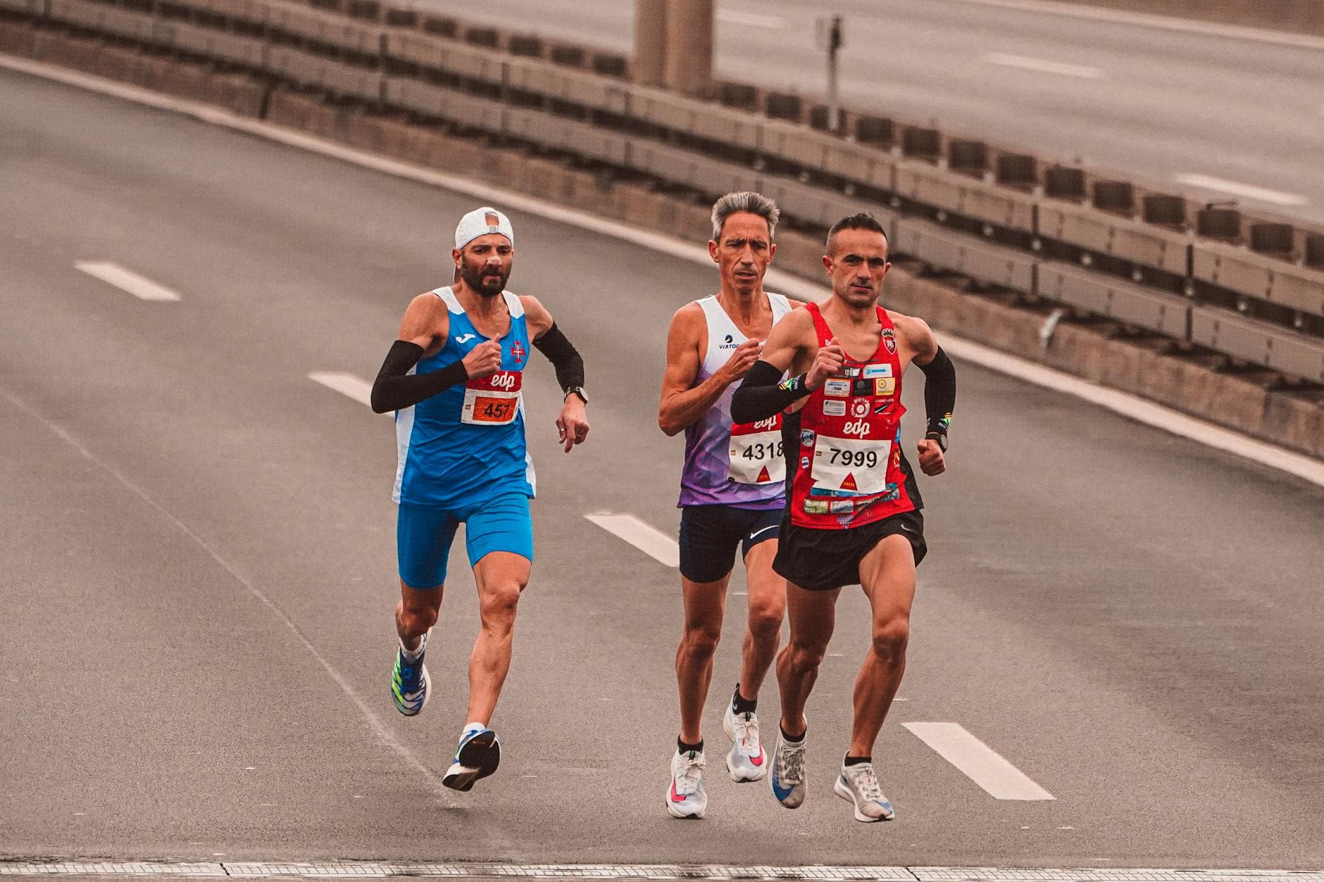Three male marathon runners on a city street showcasing endurance and competition. - running tips for beginners