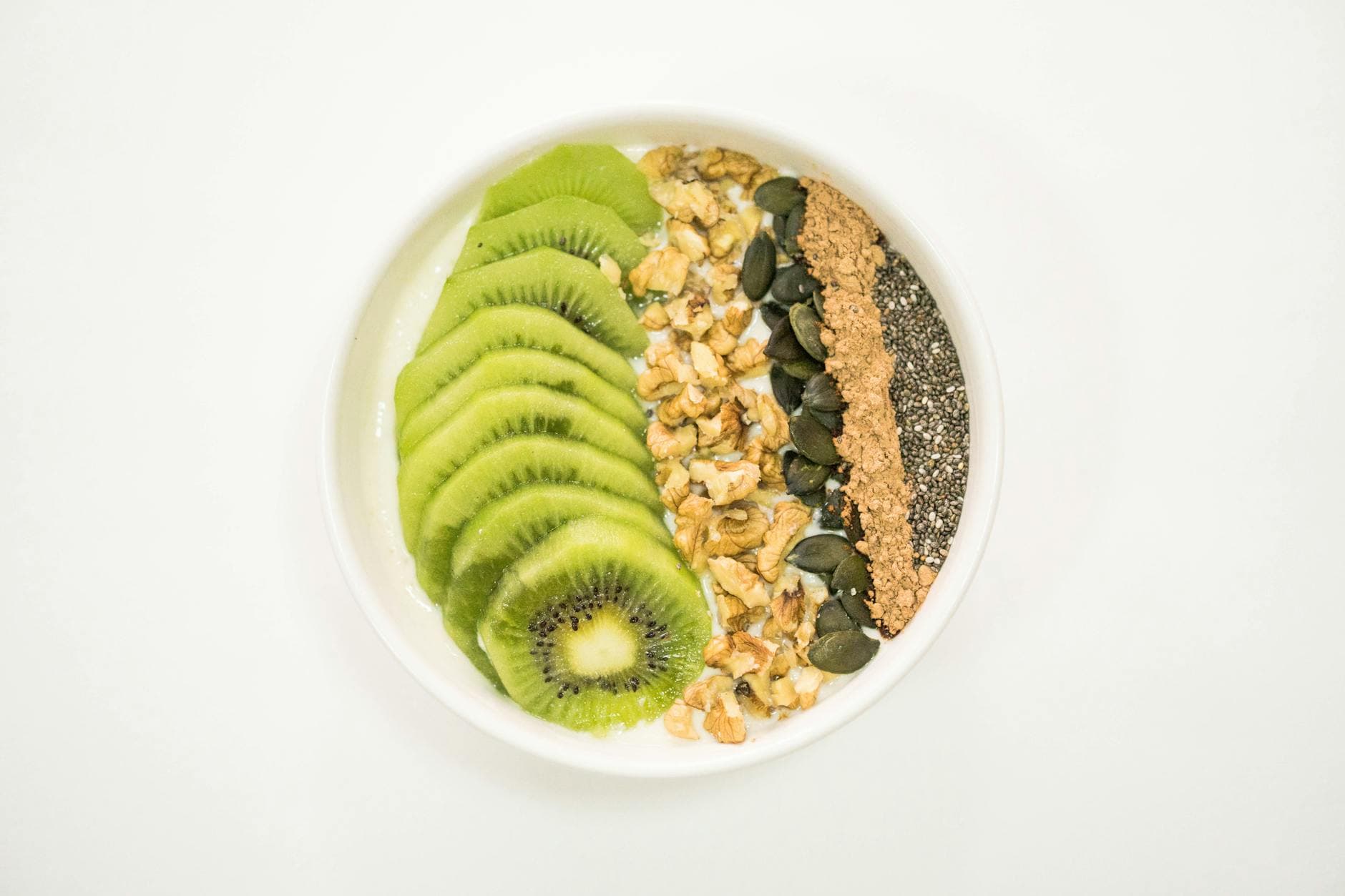 A vibrant smoothie bowl with kiwi, nuts, seeds, and yogurt, ideal for a nutritious breakfast. - spring energy breakfast