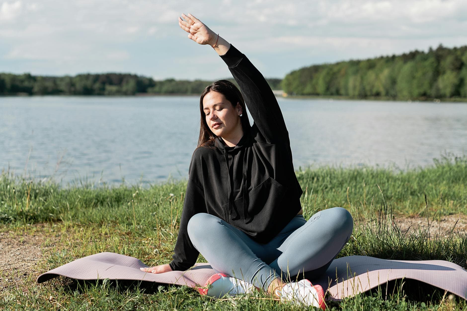 Woman enjoying a relaxing yoga session by a scenic lakeside. Perfect outdoor wellness setting. - spring exercise mood