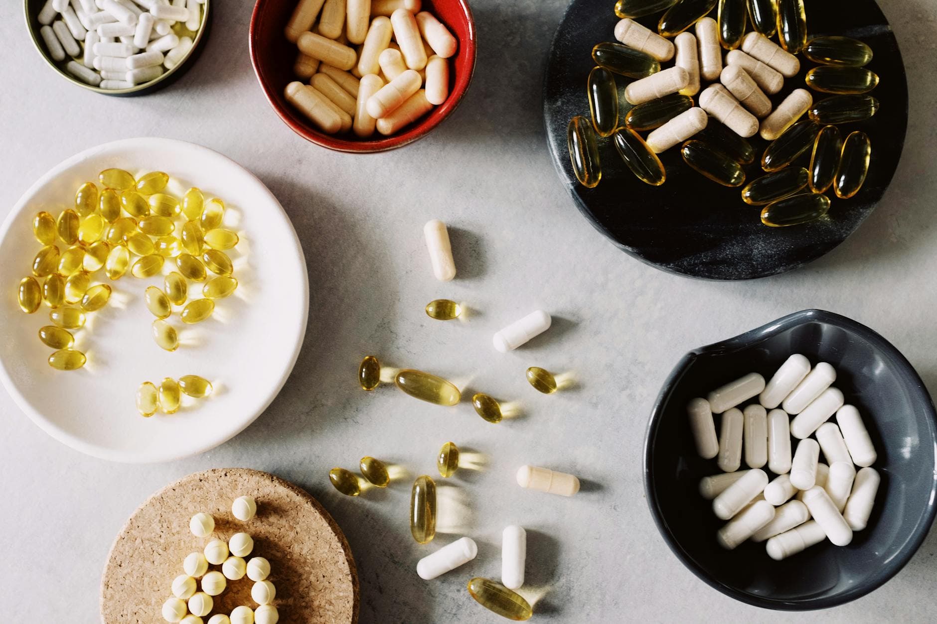 Various pills and supplements in bowls on a marble surface, ideal for healthcare contexts. - vitamin d mood
