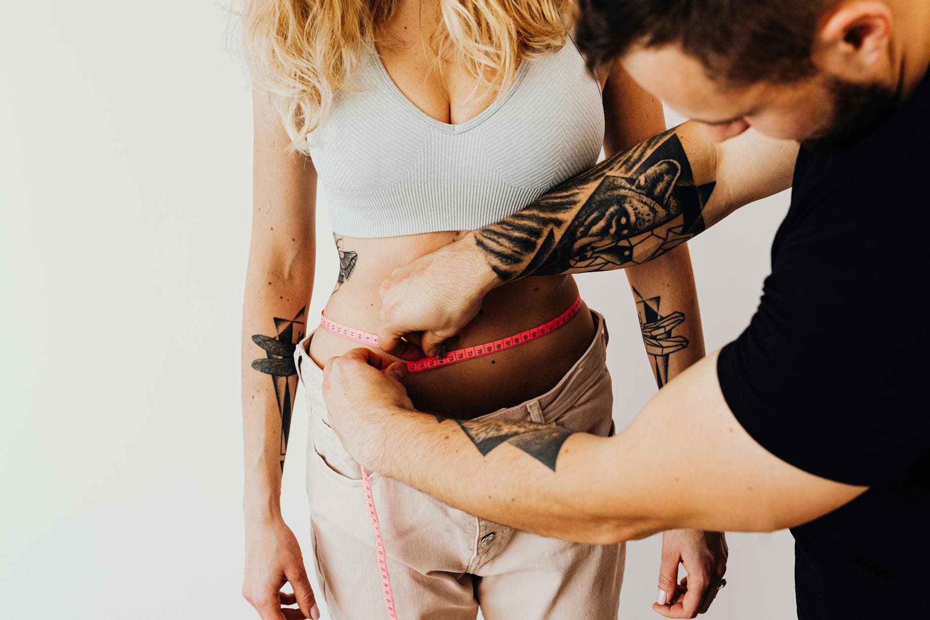 A man measures a woman's waist with a tape measure, focusing on fitness and health goals. - weight loss jumpstart