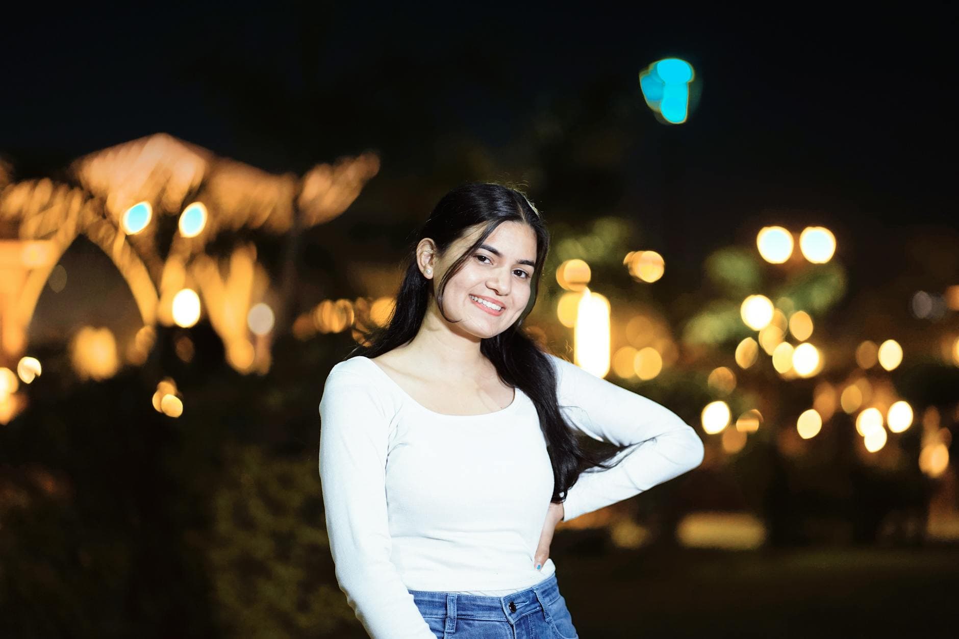 Smiling woman poses in a nighttime cityscape with blurred lights. - how to fix bad posture