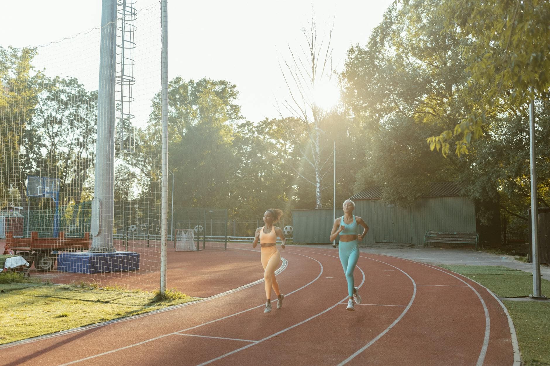 Two women jogging on an outdoor track, enjoying exercise and fitness in the morning sun. - morning workout benefits