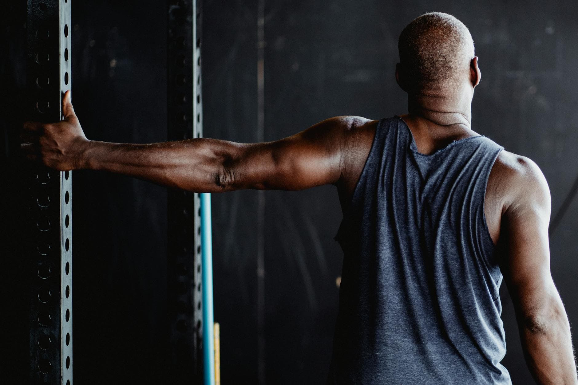 An athletic man stretching his arm in a gym, showcasing strength and flexibility. - shoulder flexibility exercises