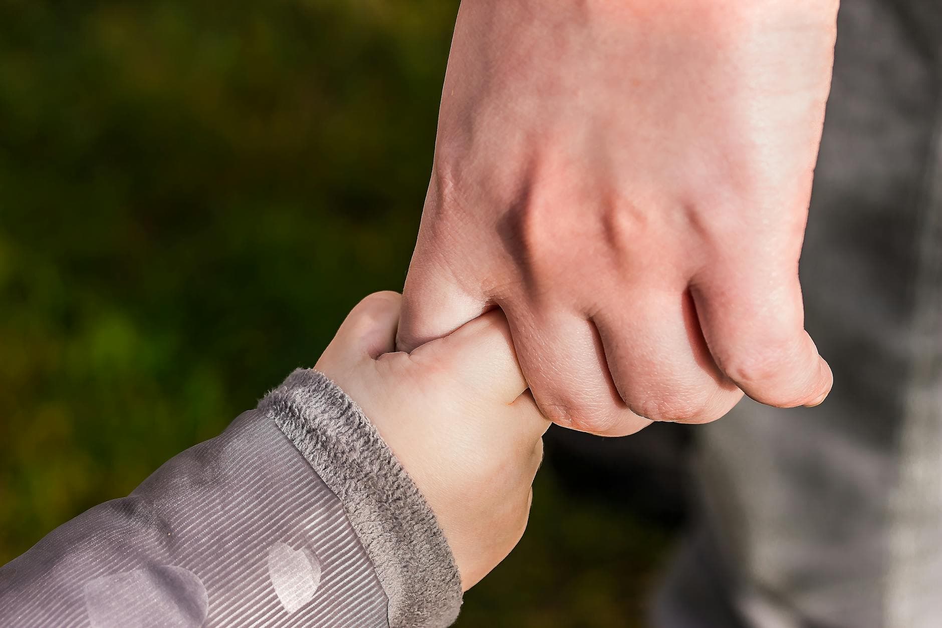 A close-up of a child and parent holding hands in a park, symbolizing love and trust. - best magnesium supplement