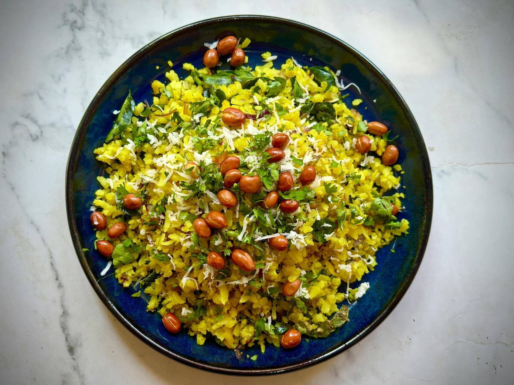Delicious Indian poha with peanuts and herbs on a vibrant plate. - easy healthy meals