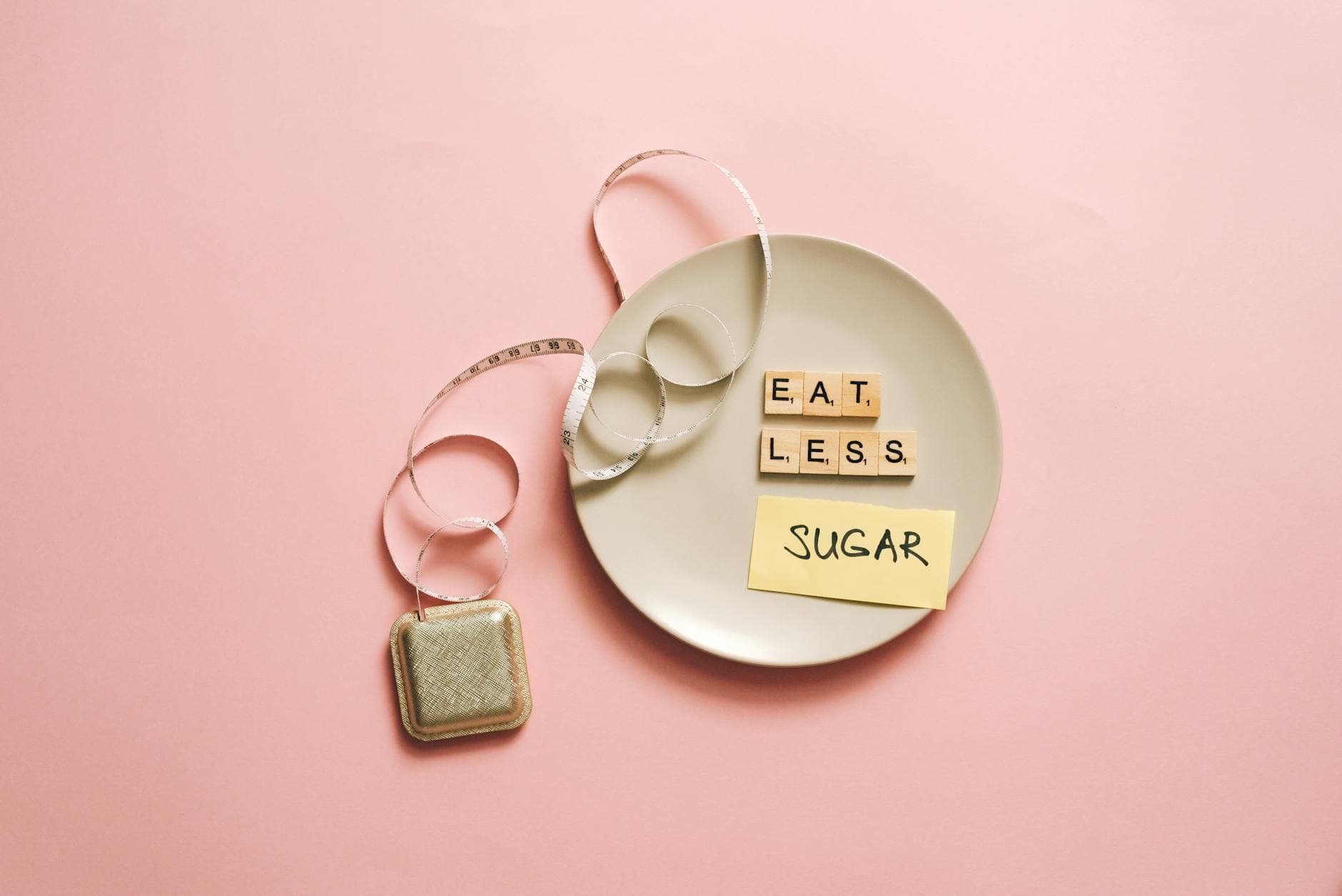 Flat lay of a plate with scrabble tiles spelling 'Eat Less Sugar,' accompanied by a tape measure, symbolizing healthy eating. - healthy diet plan